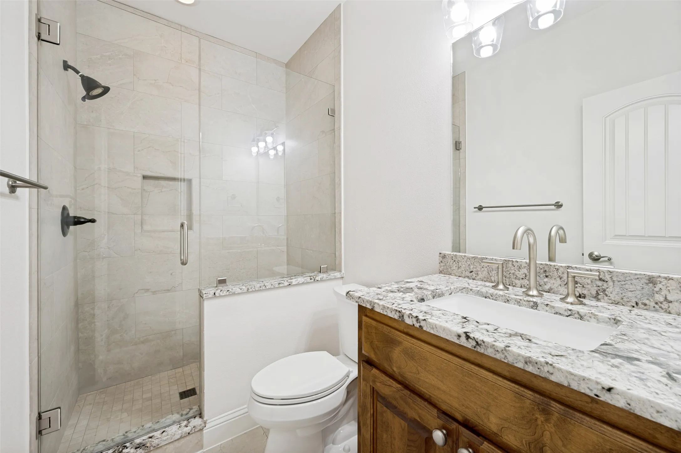 The private upstairs bath is beautifully finished with granite countertops, a custom vanity, and a frameless glass walk-in shower with designer tile, providing comfort and convenience for guests or extended family.