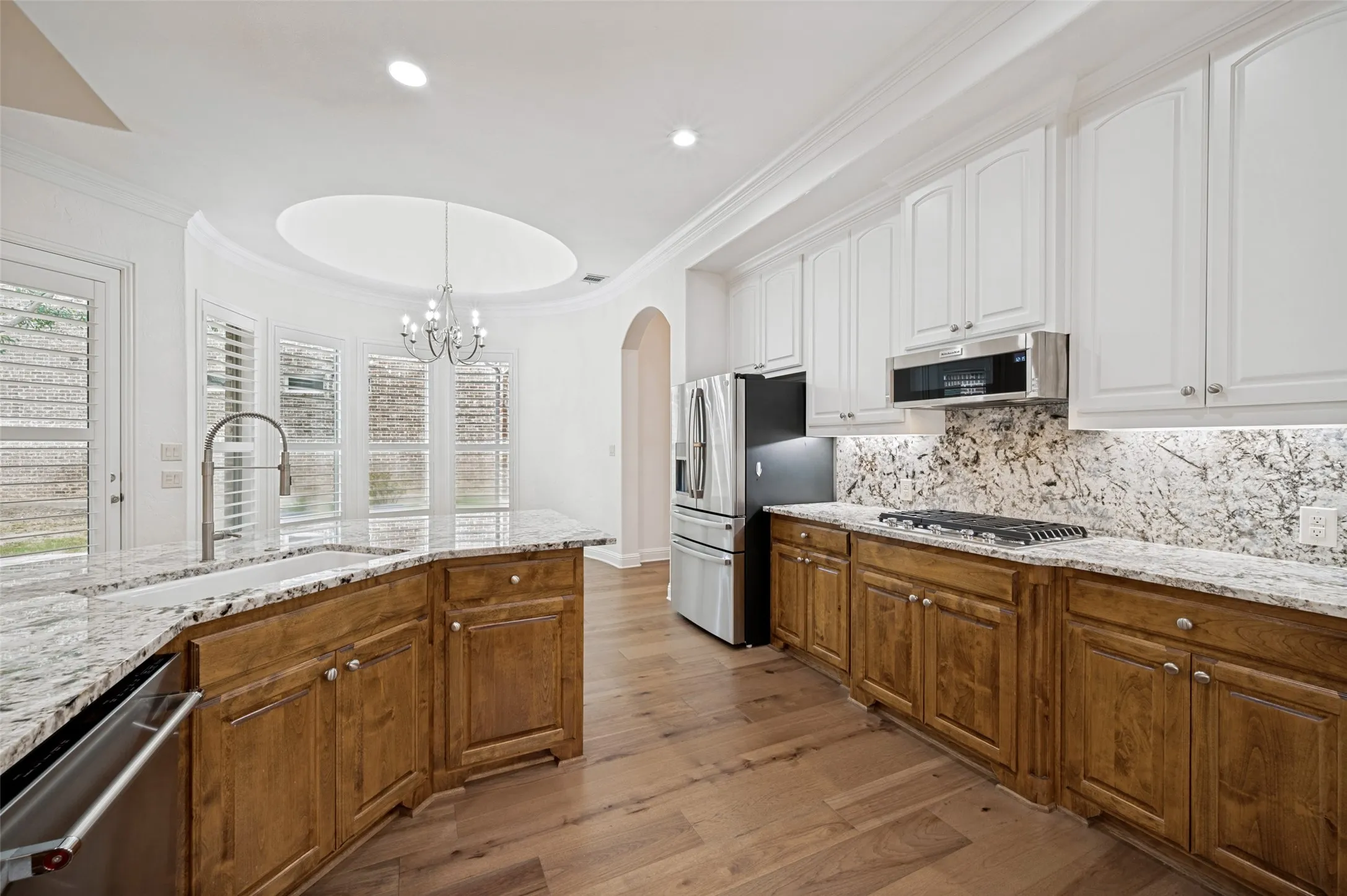 The chef's kitchen is designed to impress with abundant custom cabinetry, granite countertops, a designer tile backsplash, stainless steel appliances, a gas cooktop, and generous prep space—perfect for entertaining and everyday living.