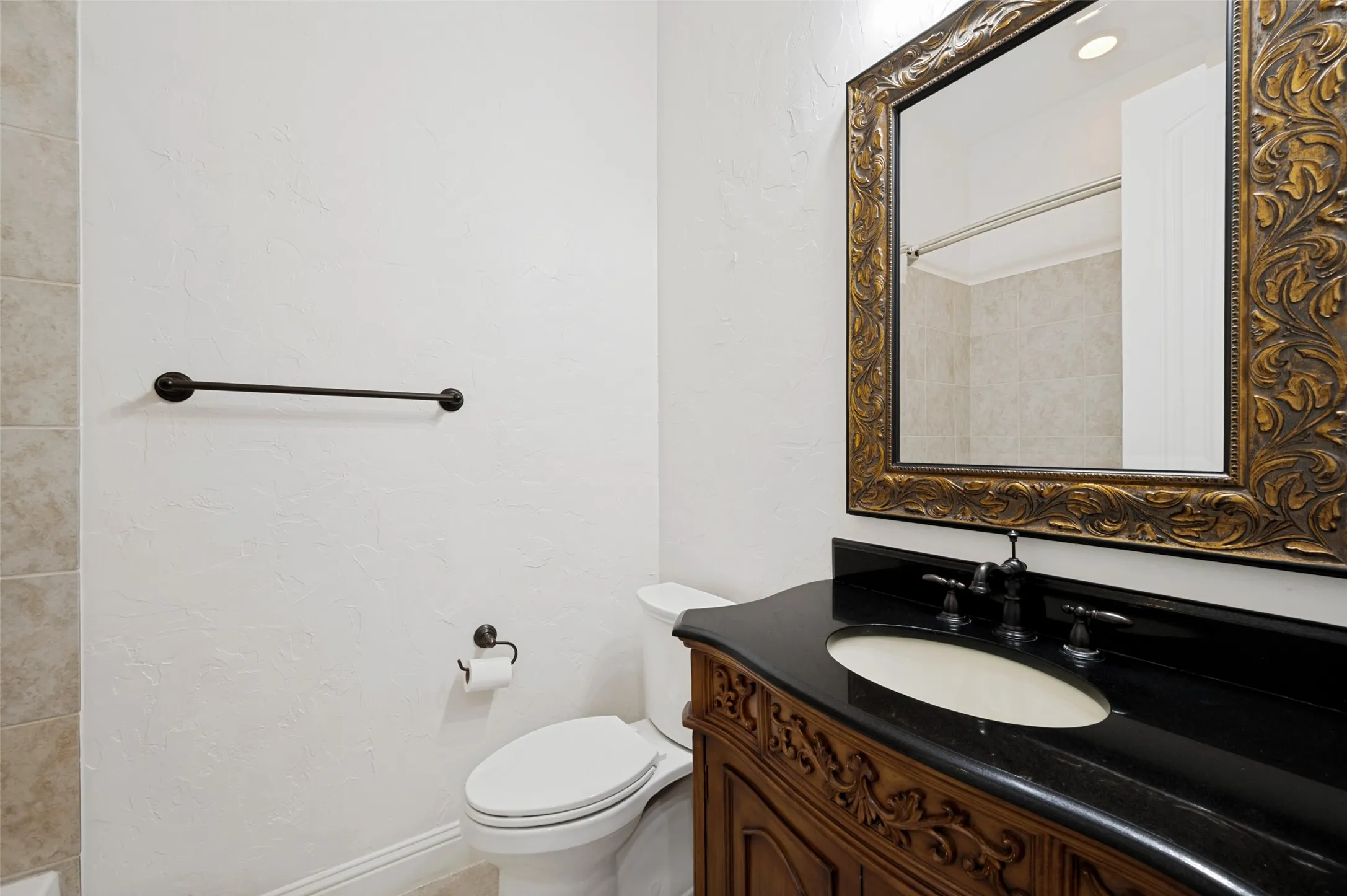 This beautifully appointed secondary bath features an elegant furniture-style vanity with granite countertops, designer fixtures, an oversized framed mirror, and a tiled tub/shower combination, offering comfort and style for family and guests.