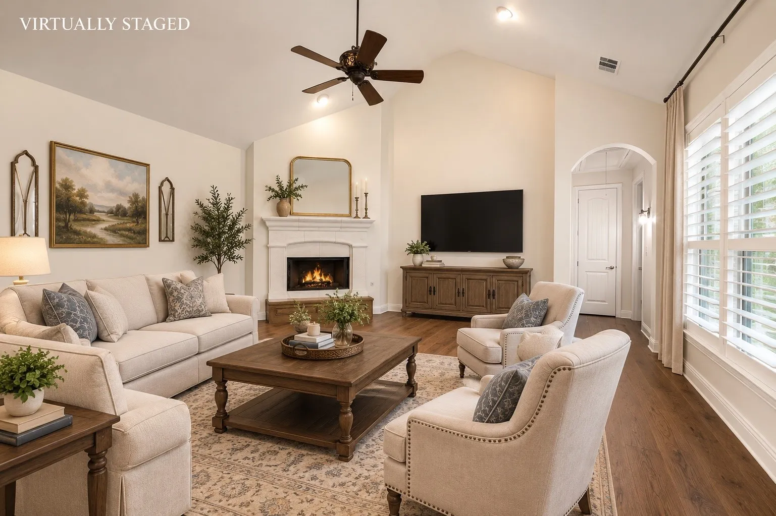 The spacious family room showcases soaring vaulted ceilings, rich hardwood floors, a beautiful cast stone fireplace, and expansive windows with plantation shutters, creating a warm and inviting space for relaxing or entertaining.