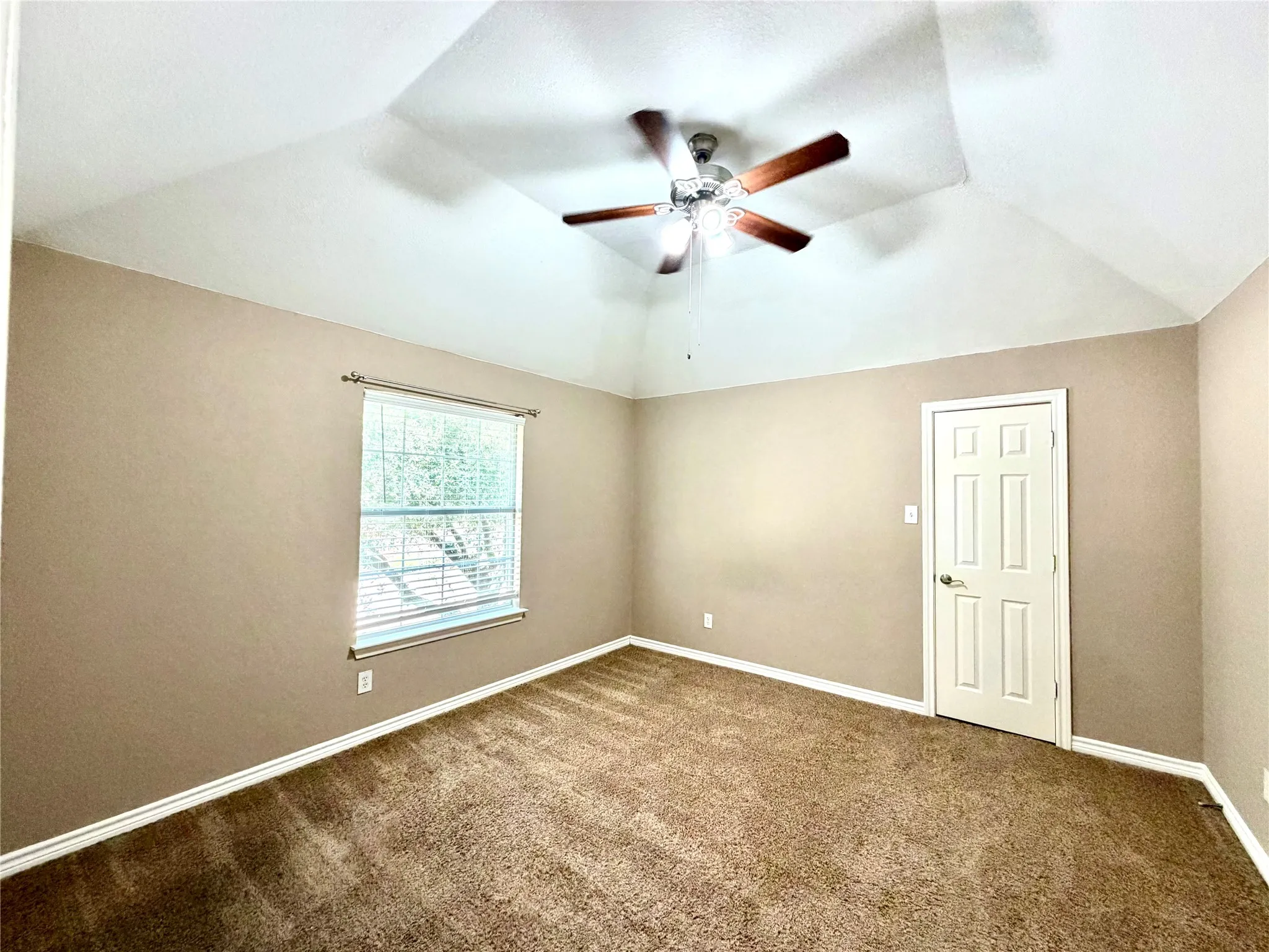 Vaulted ceiling with an illuminated ceiling fan, neutral wall tones, window with blinds, and carpeted flooring