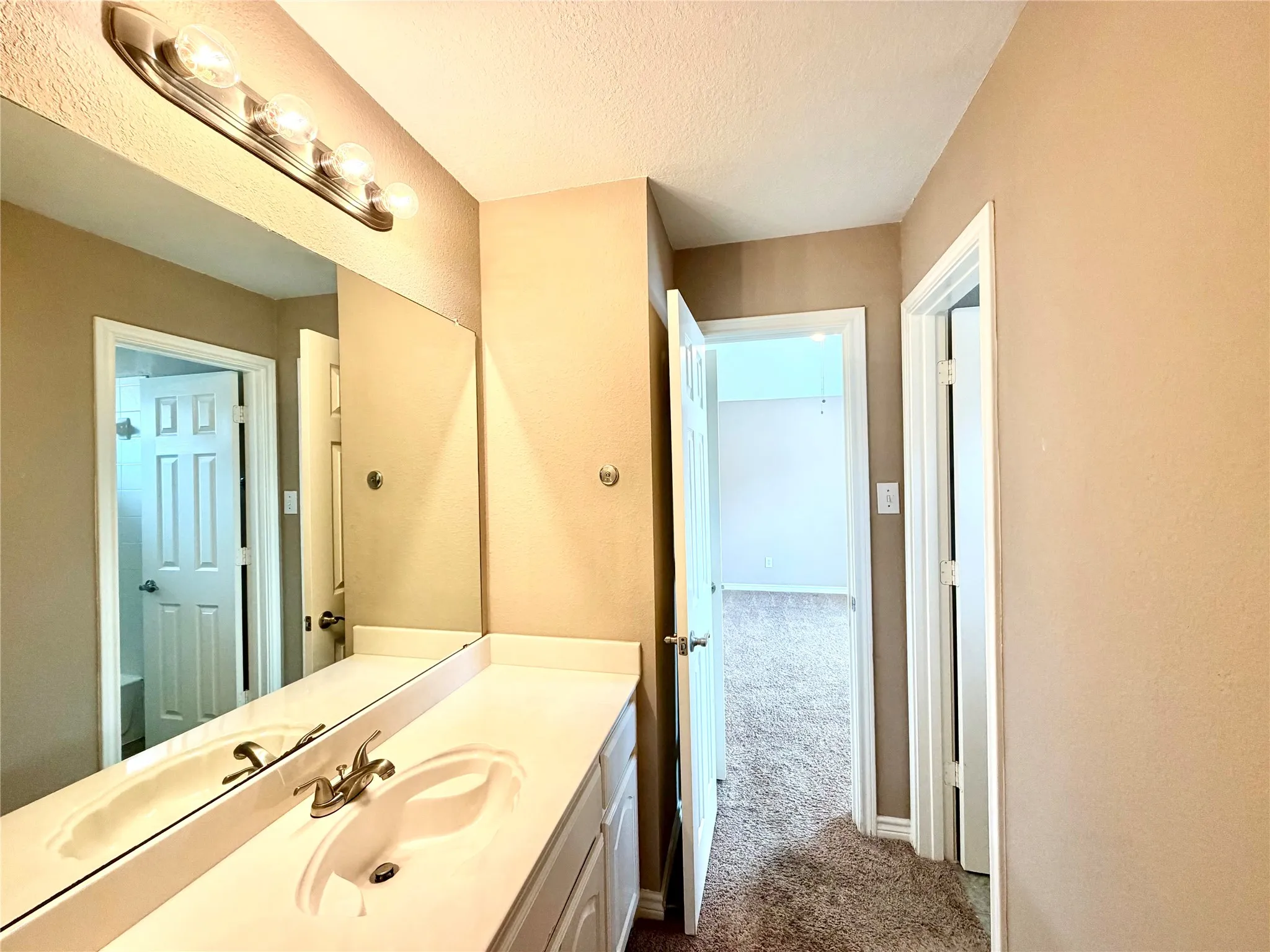 Vanity with an integrated sink and brushed nickel faucet, illuminated by a four-bulb vanity light fixture