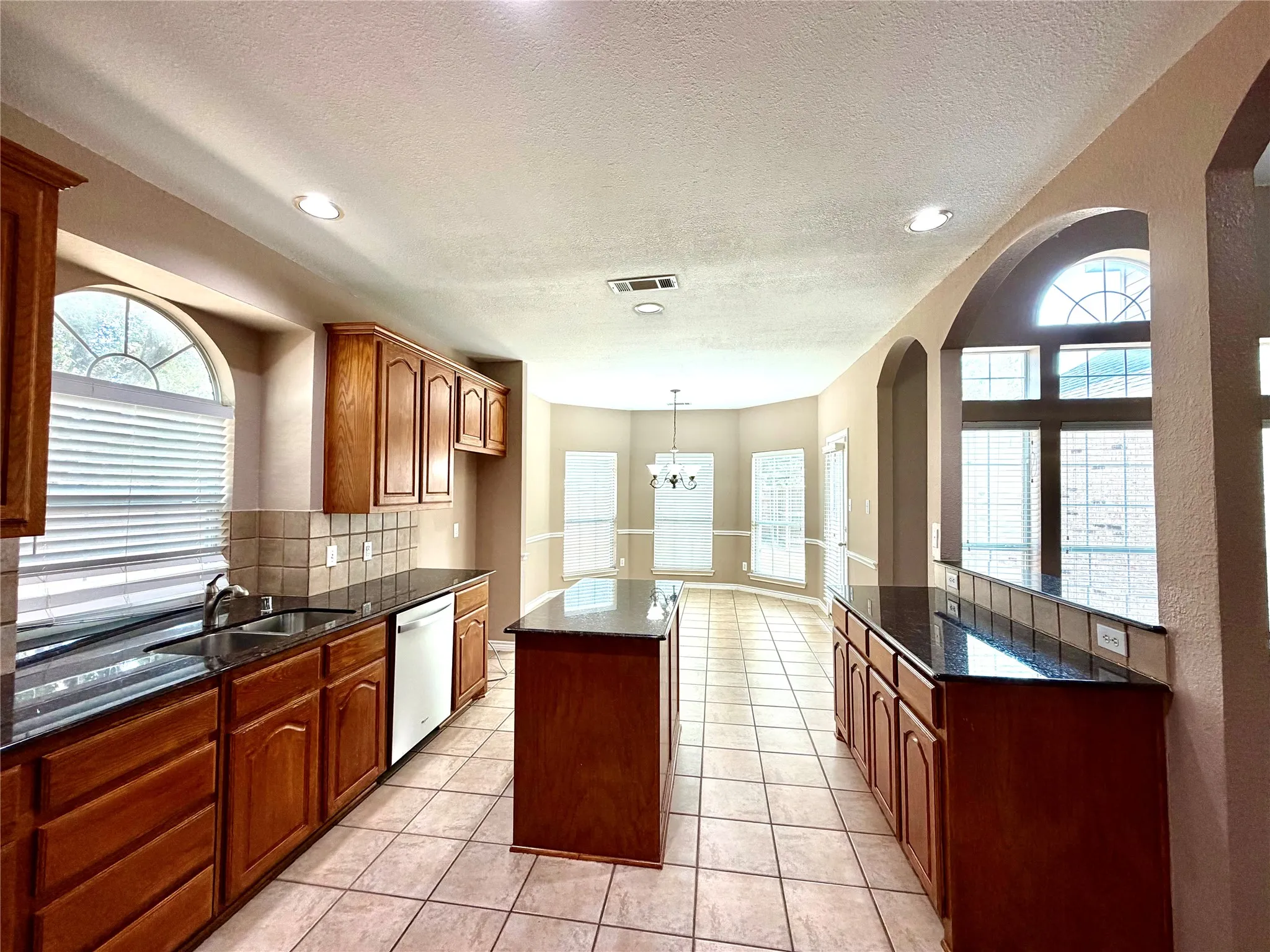 Kitchen featuring an island, recessed lighting, tile flooring, and dark countertops