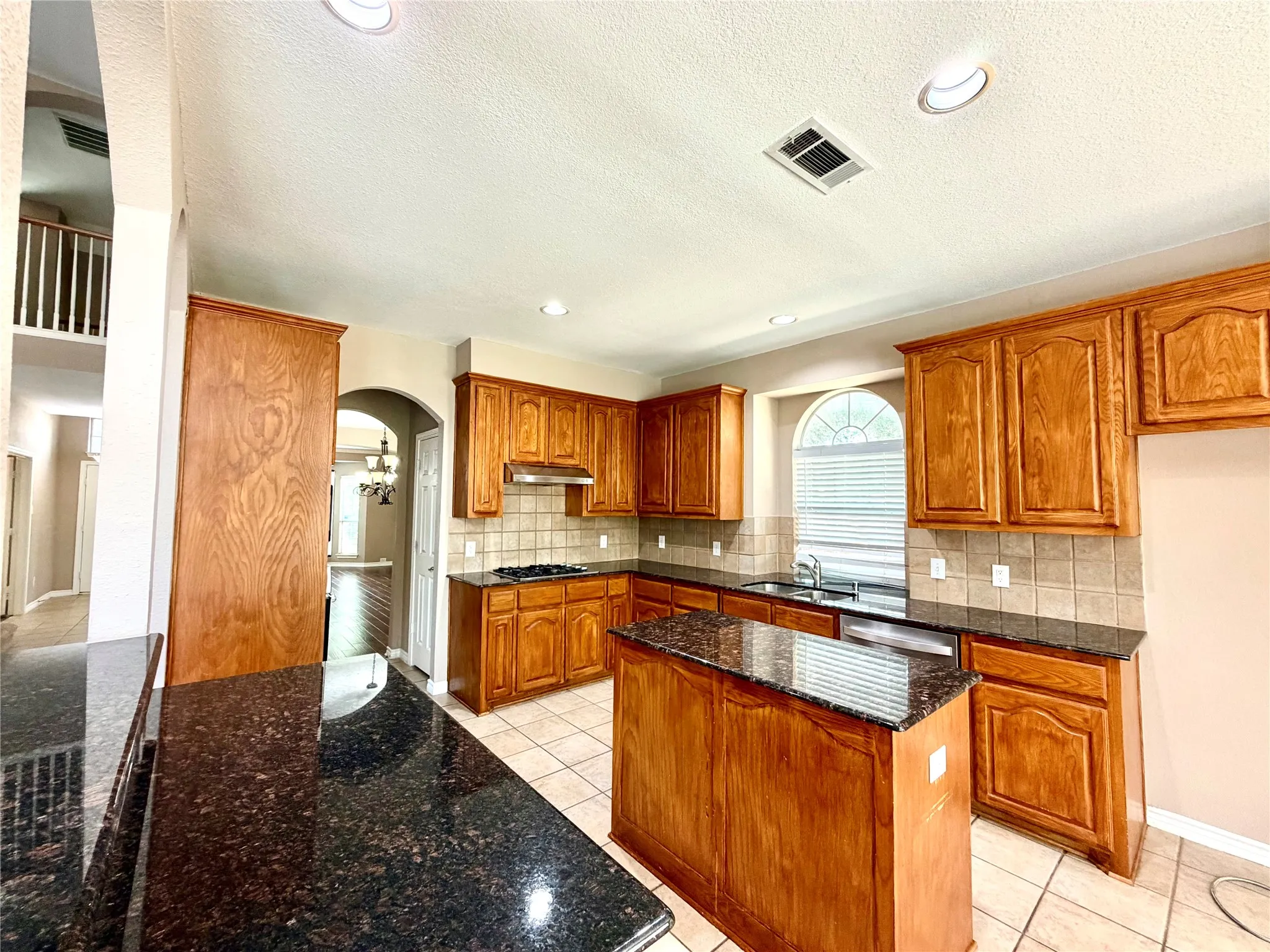 Kitchen featuring wood cabinetry, granite countertops, a tiled backsplash, and recessed lighting