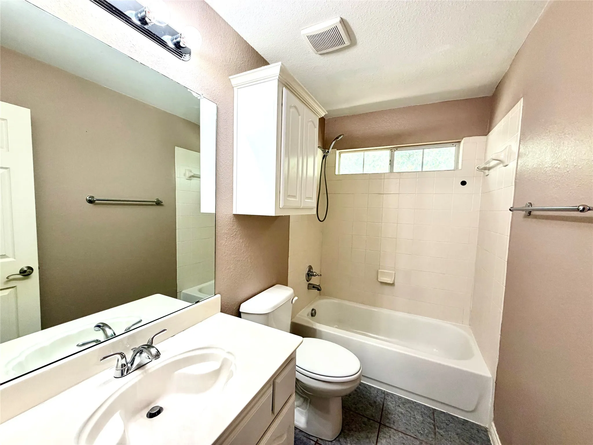 Bathroom featuring a built-in vanity with an integrated sink, a large wall mirror, and a combination shower/tub with white tile surround