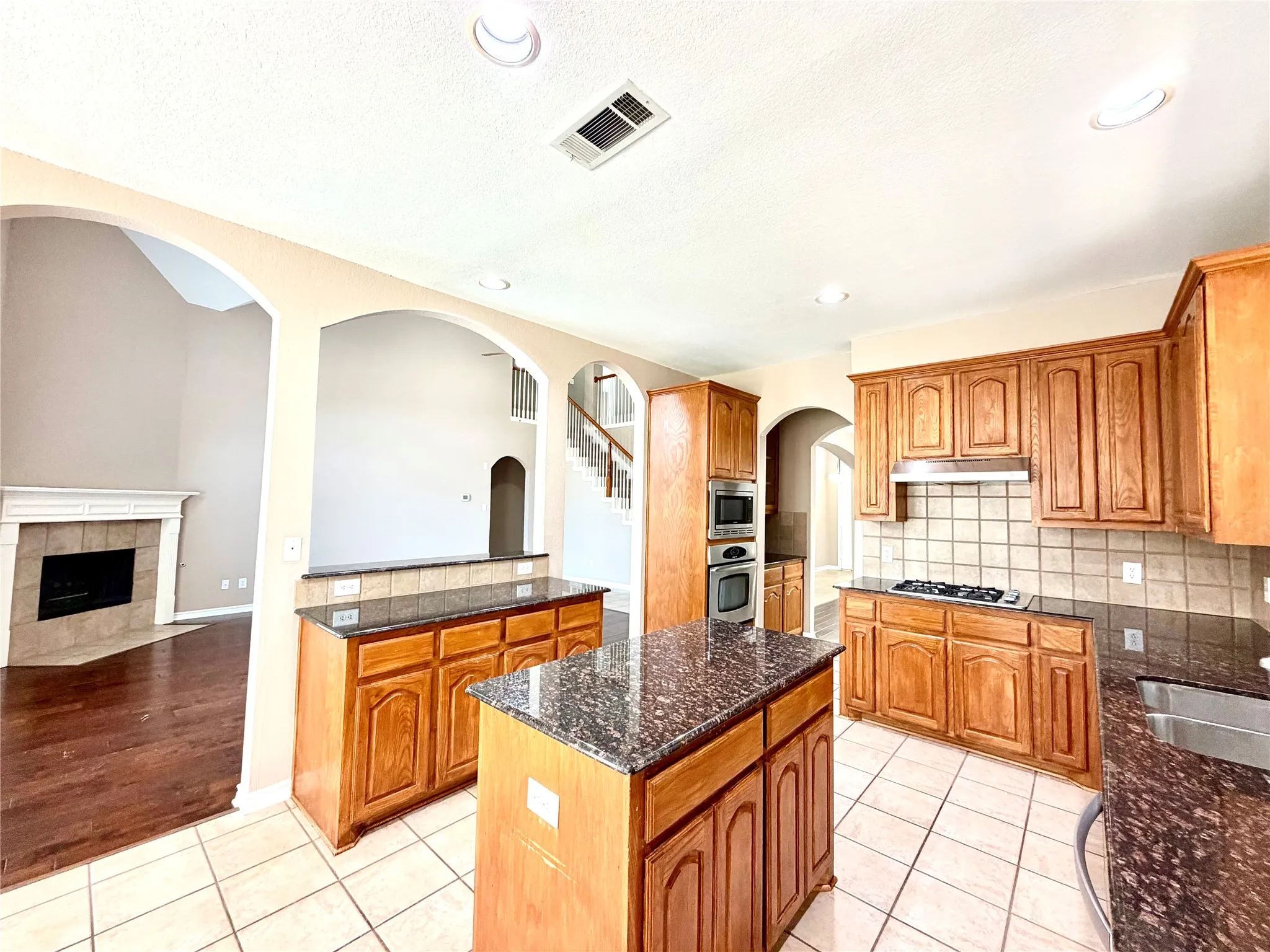 Kitchen featuring a central island, wood cabinetry, built-in stainless steel appliances, and tile flooring