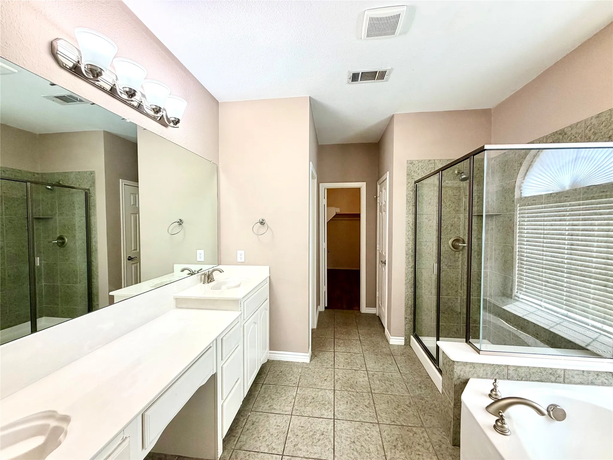 Dual vanity with white cabinetry, large vanity mirror, and brushed nickel fixtures
