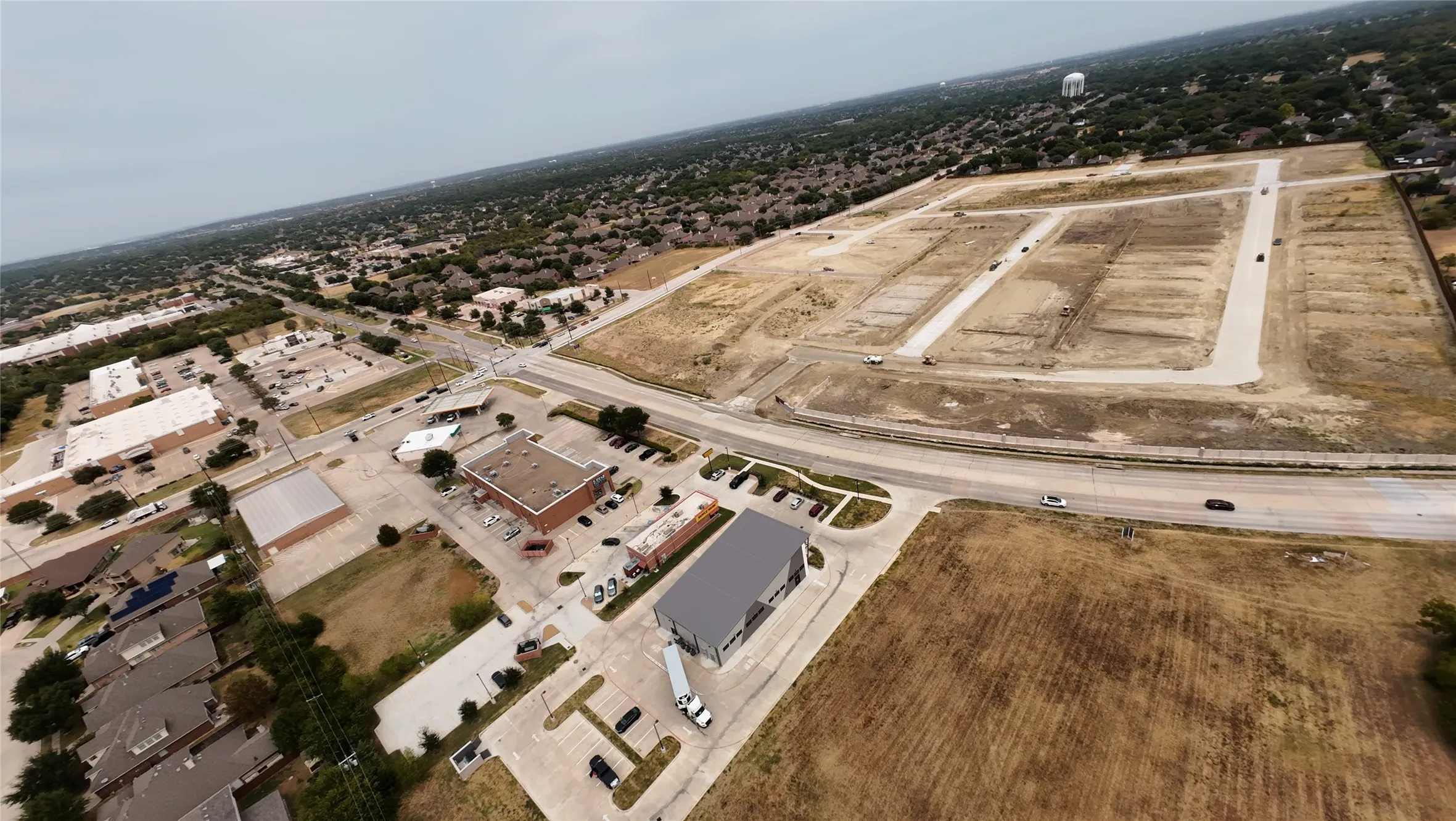 Expansive land parcel with visible road infrastructure, surrounded by established residential areas and commercial properties
