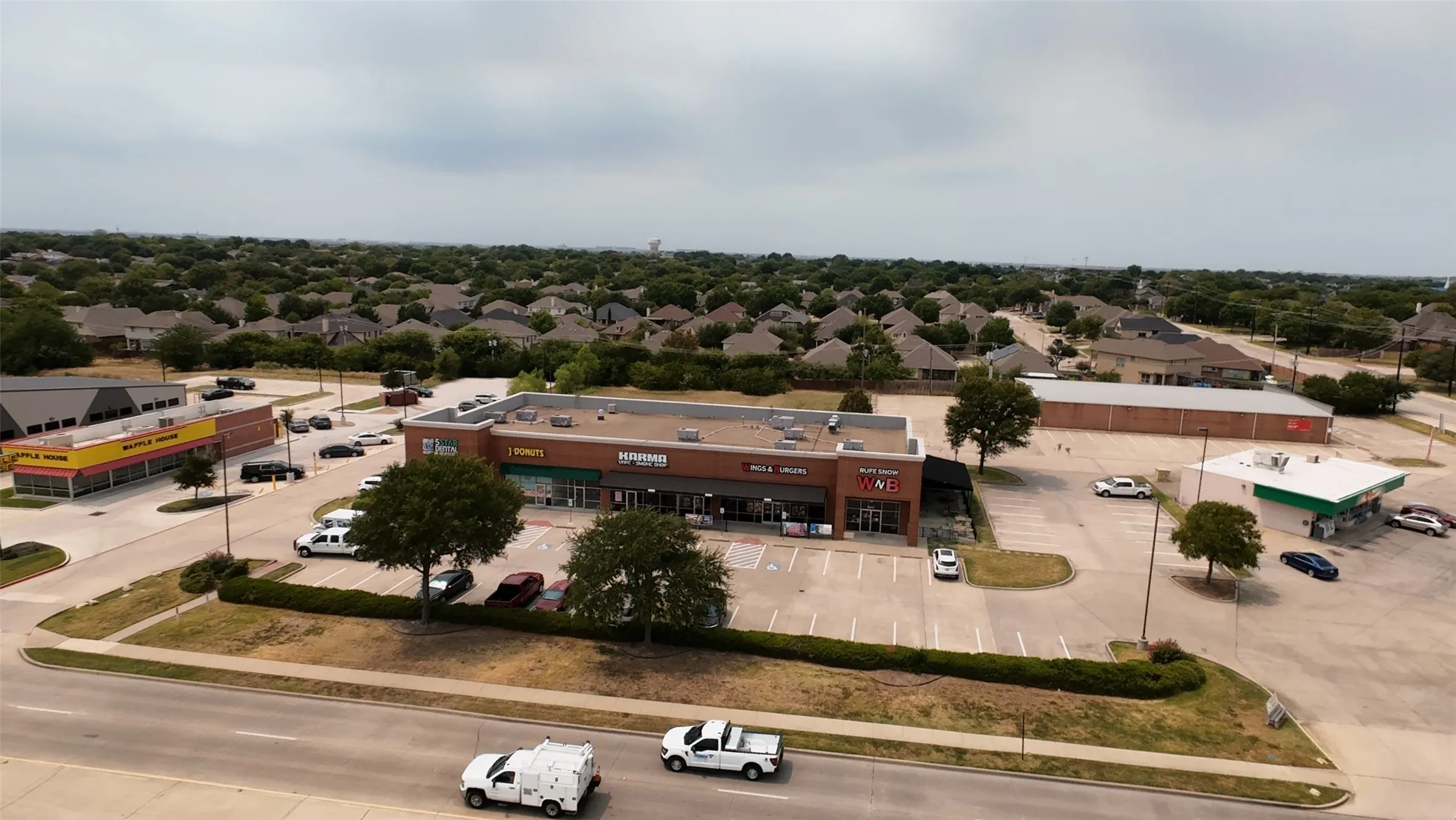 Commercial building with multiple storefronts, ample paved parking, and direct street access