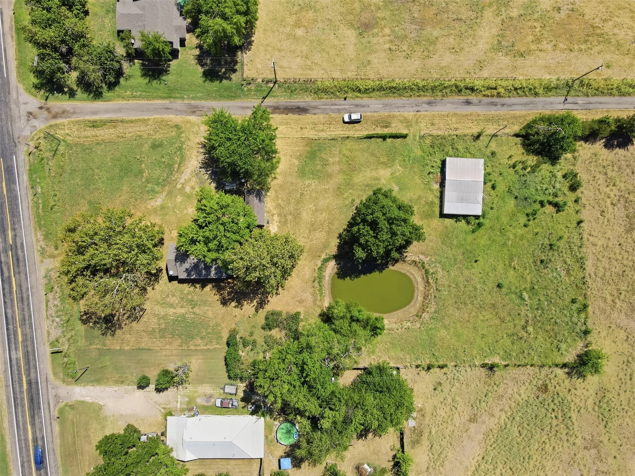 Expansive property featuring a private pond, multiple mature trees, and multiple outbuildings including workshop