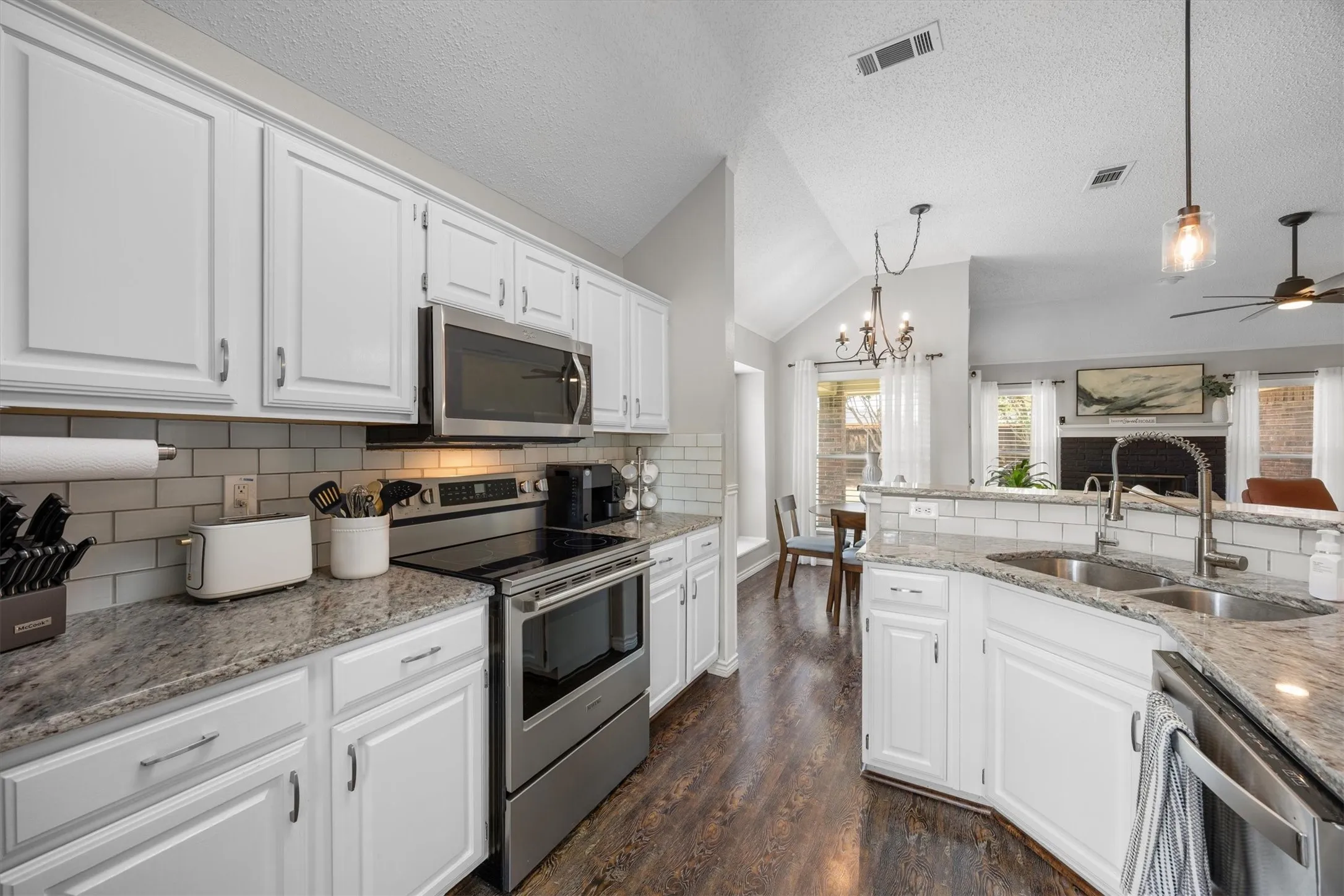 Chef's kitchen featuring white cabinetry, stainless steel appliances, subway tile backsplash.