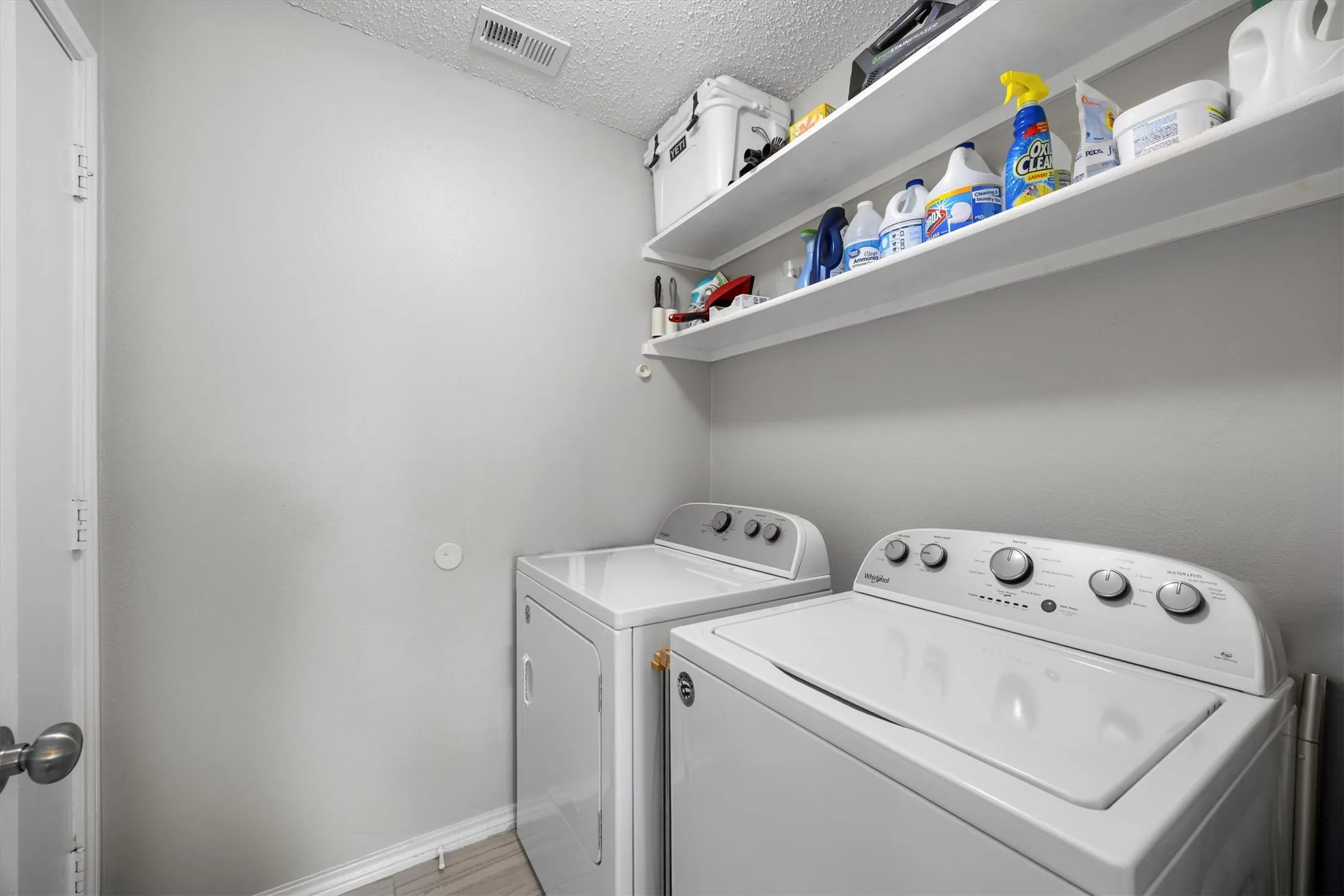 Dedicated laundry area featuring overhead shelving and light-toned walls