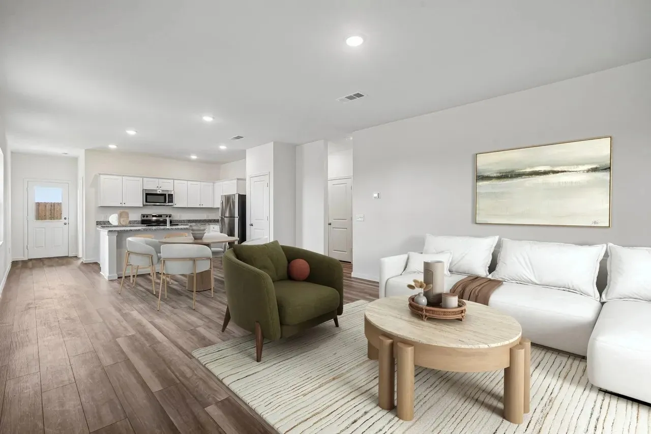 Open-concept living space featuring wood-finish flooring, recessed lighting, and a kitchen with white cabinetry and stainless steel appliances