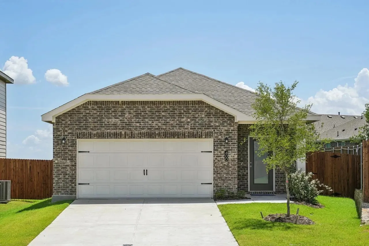 Brick facade with a gabled roofline, concrete driveway, and attached two-car garage