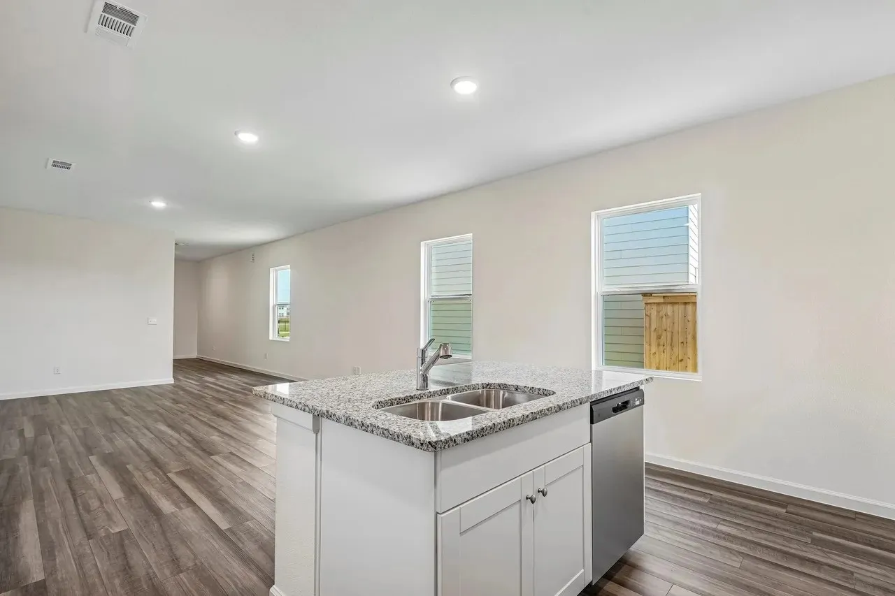 Kitchen island with granite countertop and double stainless steel sink, stainless steel dishwasher, recessed lighting, and wood-finish flooring
