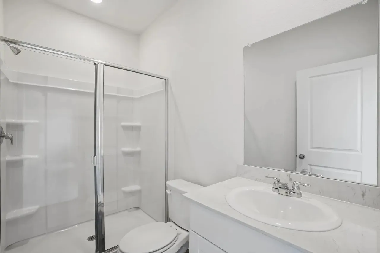 Bathroom featuring a glass-enclosed shower, a vanity with an integrated sink, a large wall-mounted mirror, and a recessed ceiling light