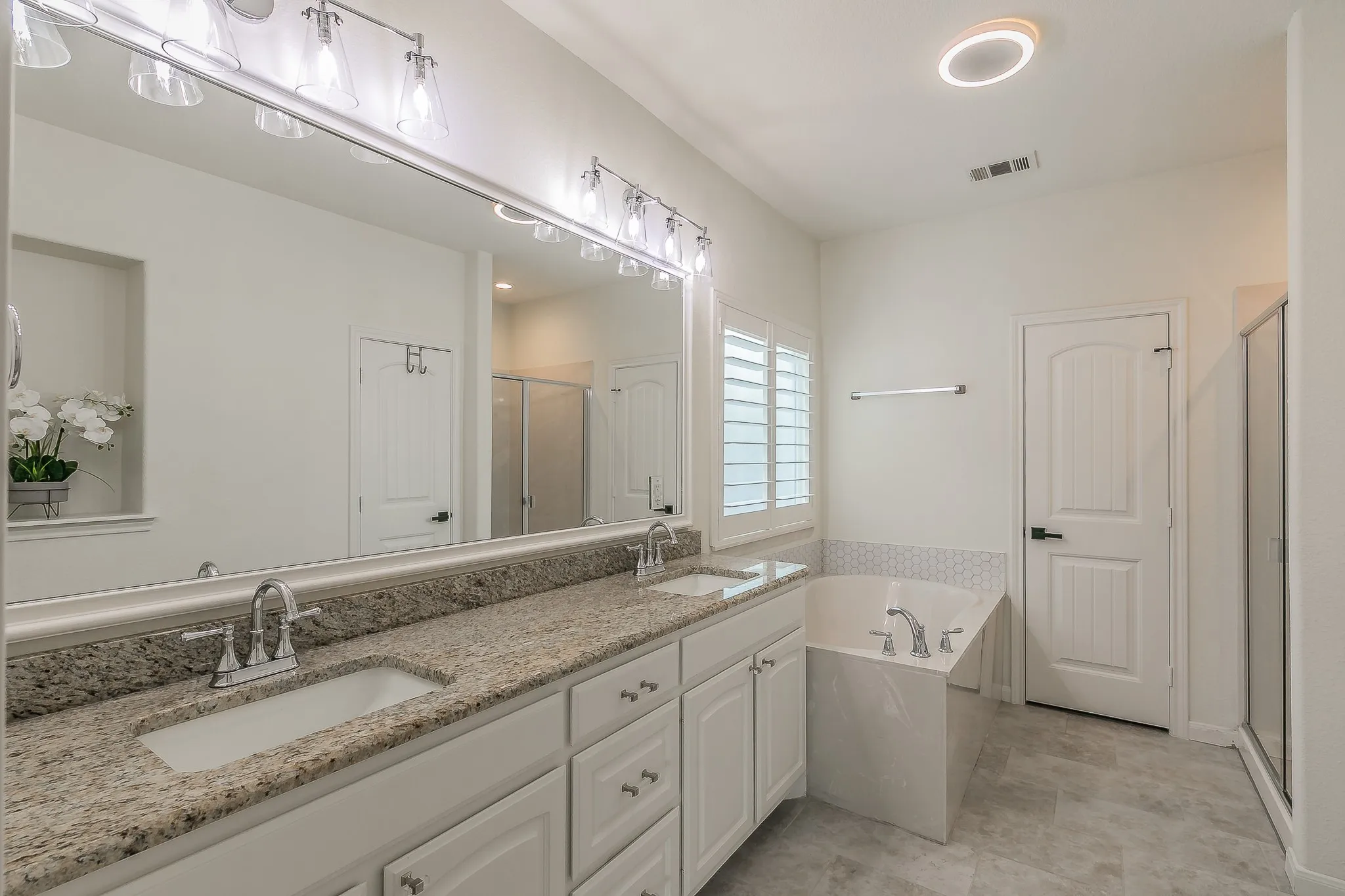 Primary bath features double sinks, granite countertops, garden tub & tiled shower with walk in closet