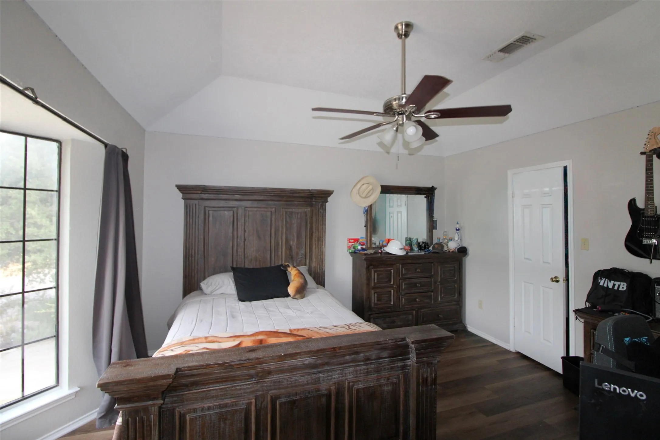 Vaulted ceiling, ceiling fan, large window, wood-finish flooring, white paneled door
