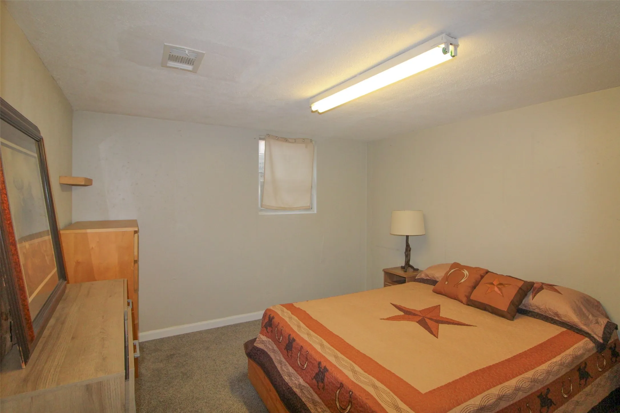 Carpeted flooring, neutral wall color, and a window with a valance