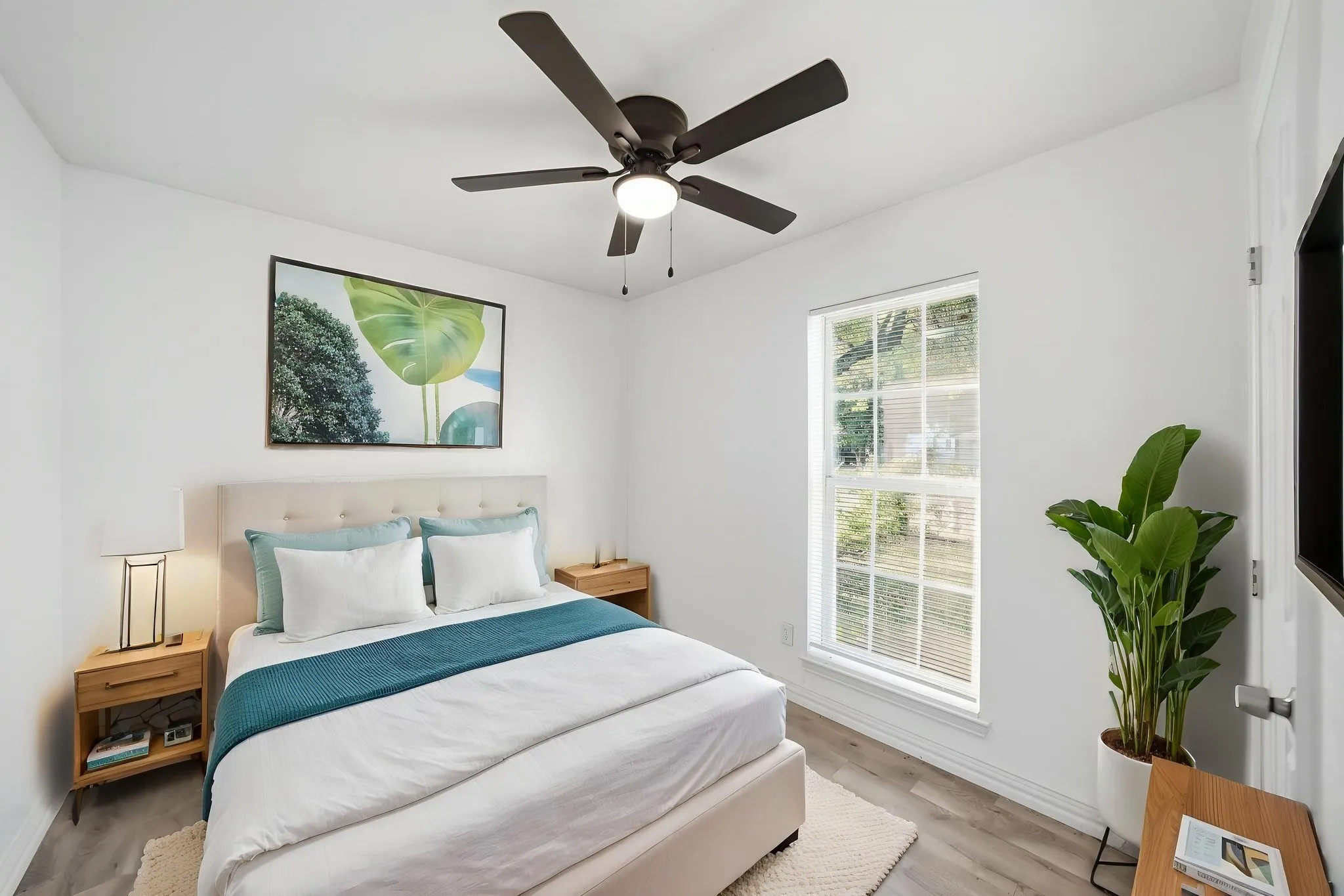 Bright bedroom featuring a ceiling fan, wood-finish flooring, a window with blinds, and white walls