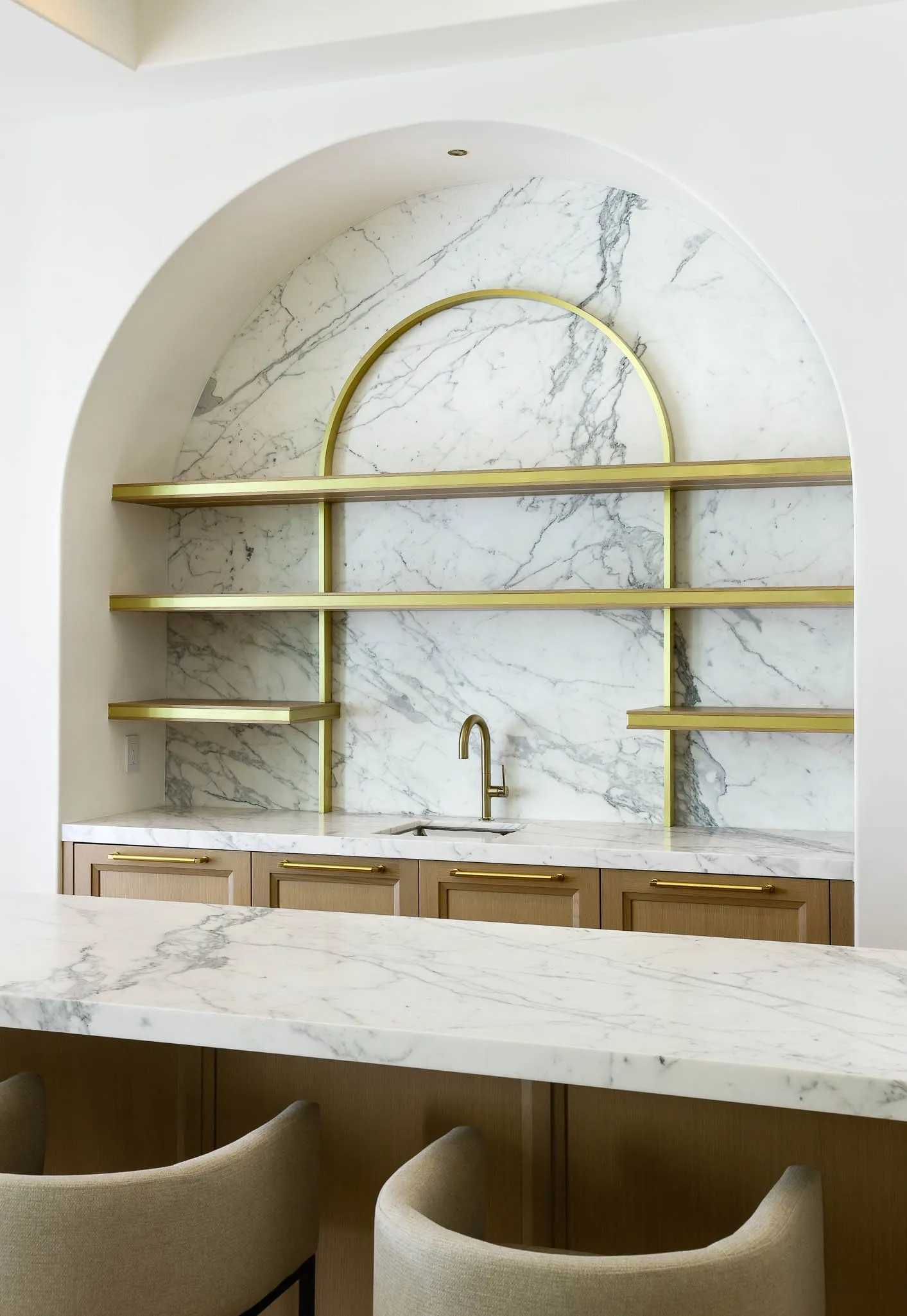 Wet Bar adjacent to Family Room featuring marble slab counterops and backsplash, Kallista sink and fixtures, Wood Mode custom cabinetry, beverage center, and climate controlled wine room with custom shelves