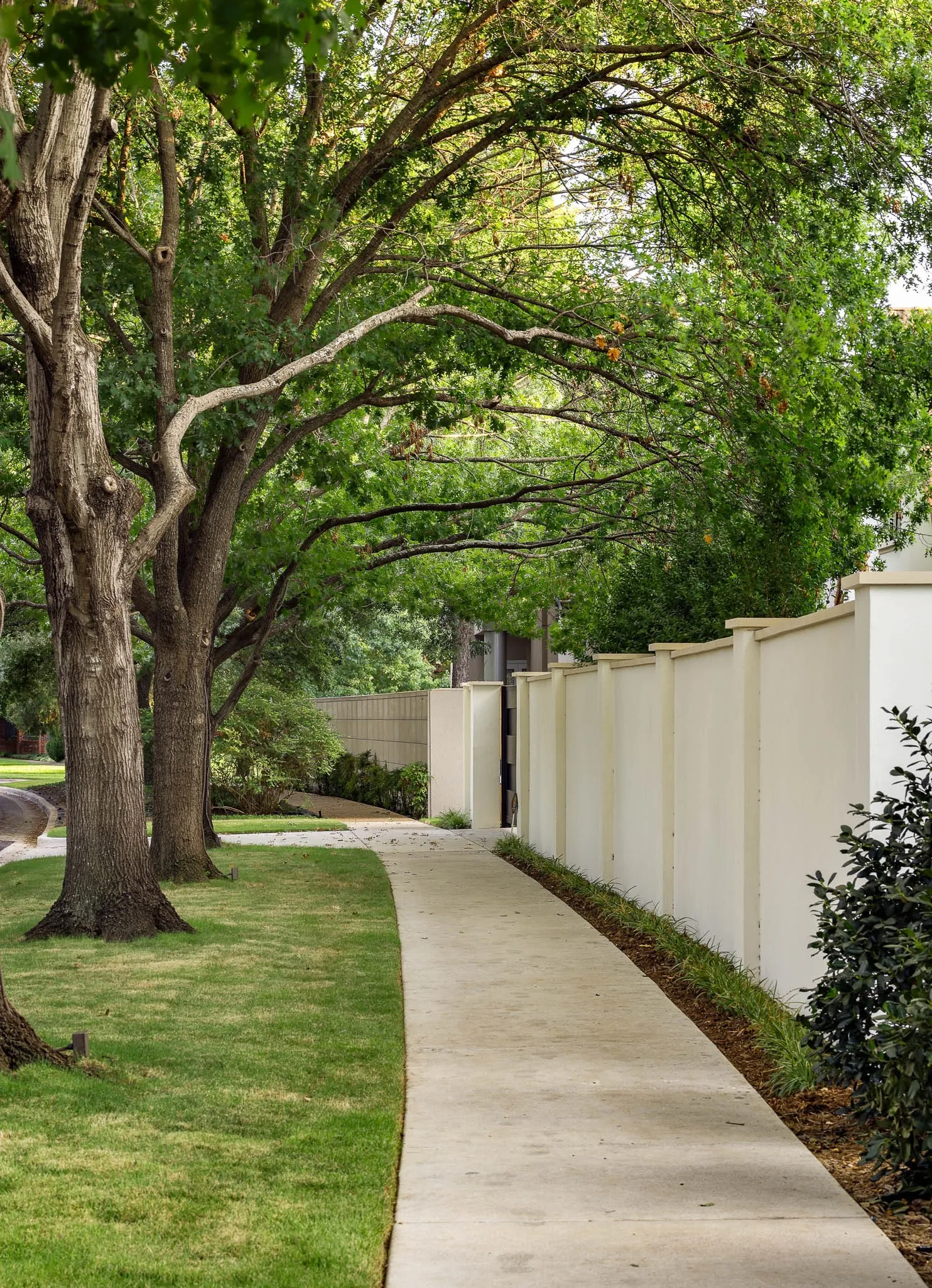 View of masonry privacy wall with landscaping and gated driveway entrance