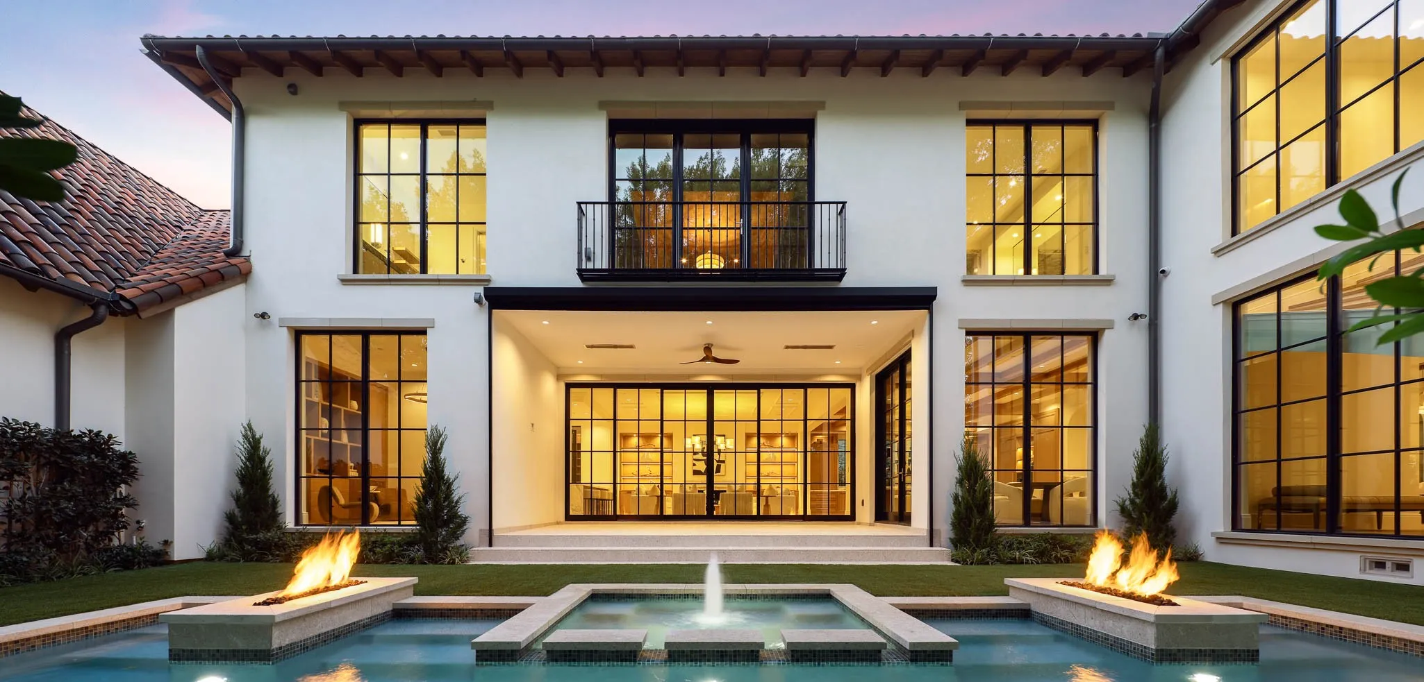 Outdoor pool and spa with water feature and linear fire accents open to landscaped backyard and climate controlled Loggia