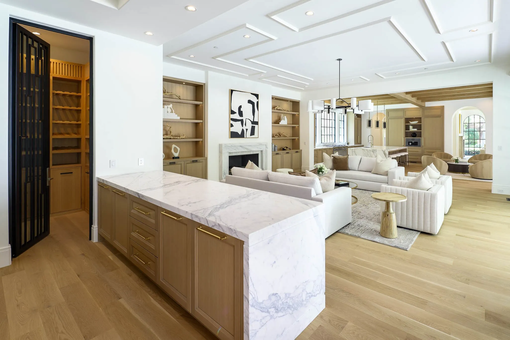 Wet Bar adjacent to Family Room featuring marble slab counterops and backsplash, Kallista sink and fixtures, Wood Mode custom cabinetry, beveraeg center, and climate controlled wine room with custom shelves