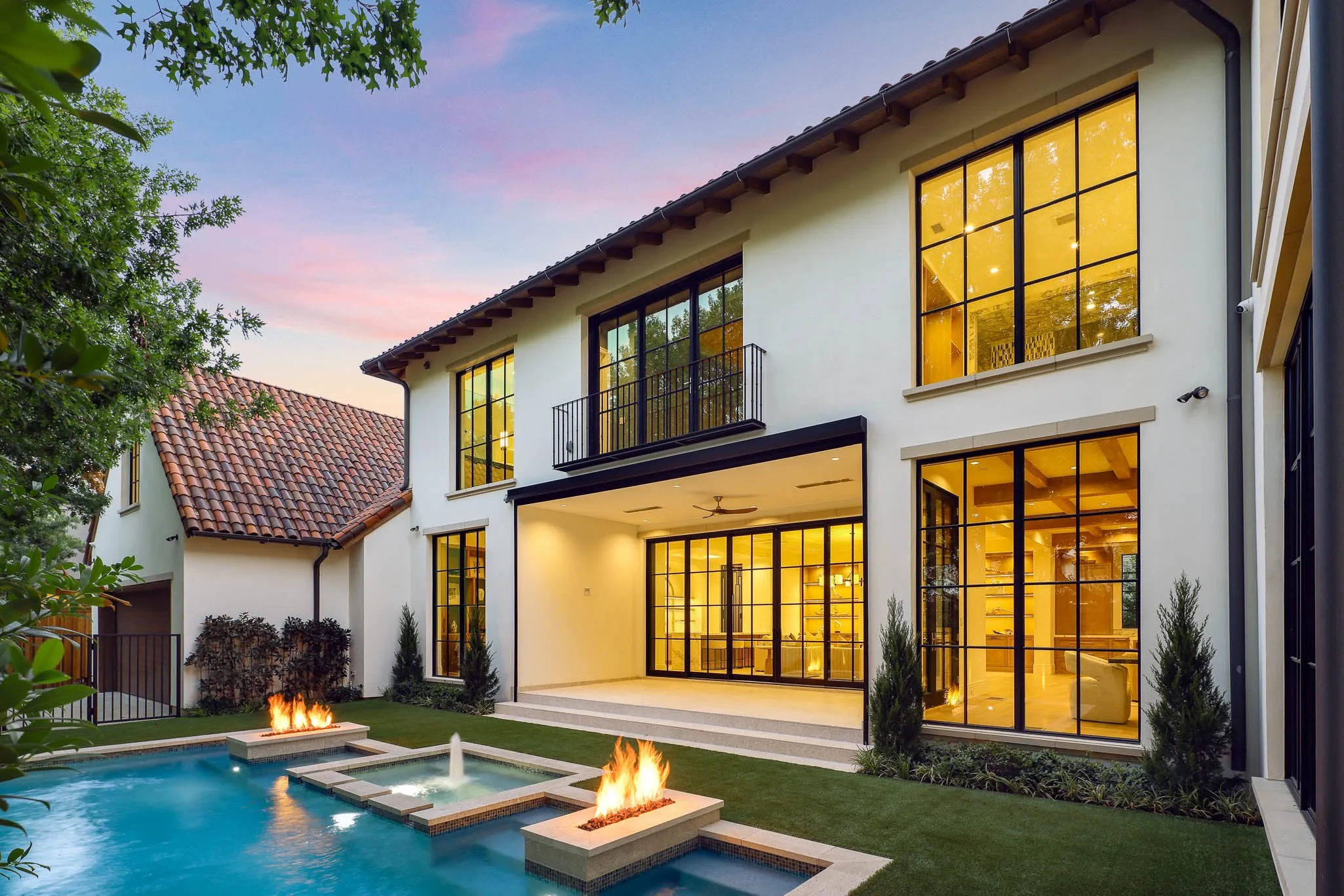 Outdoor pool and spa with water feature and linear fire accents open to landscaped backyard and climate controlled Loggia
