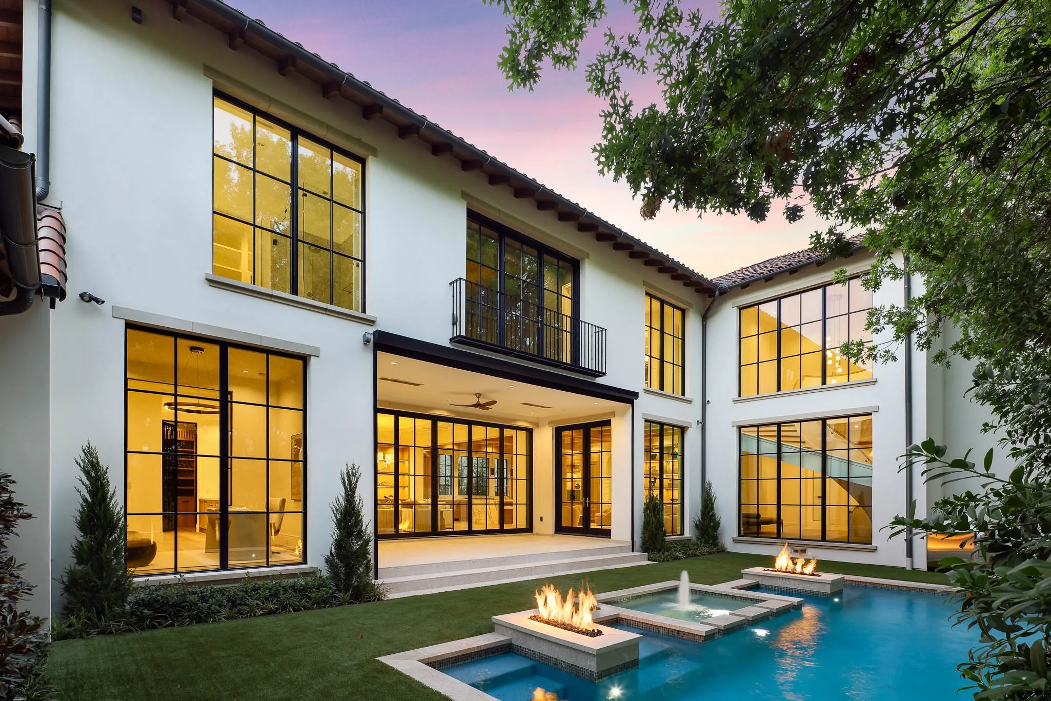 Outdoor pool and spa with water feature and linear fire accents open to landscaped backyard and climate controlled Loggia