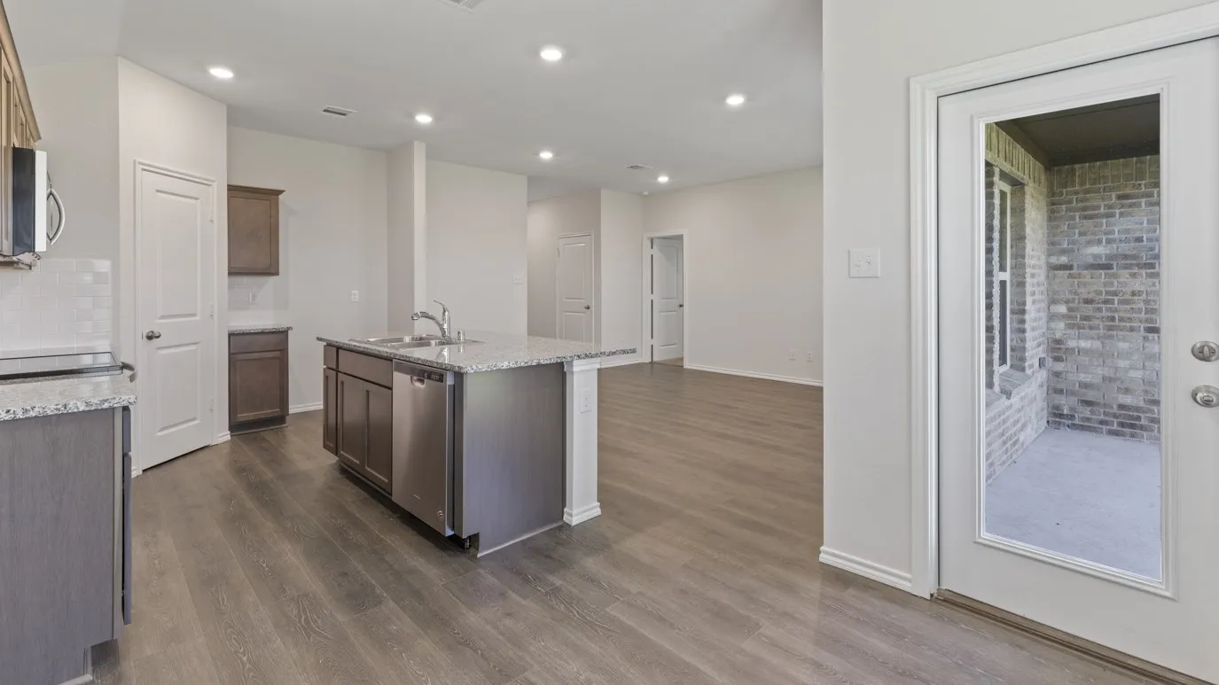 Kitchen island with granite countertops, stainless steel sink, and built-in dishwasher