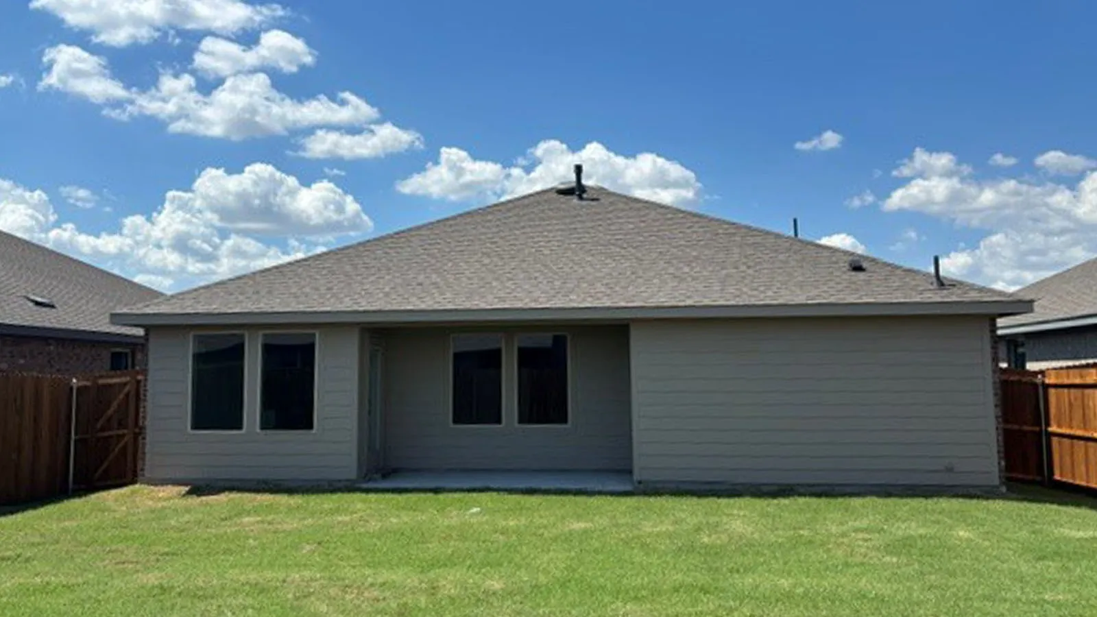 Expansive backyard with a manicured lawn, full privacy fencing, and a concrete patio