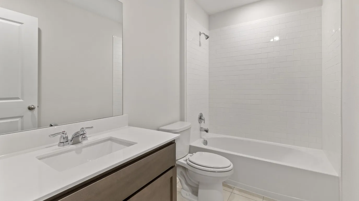 Bathroom featuring a built-in vanity with an integrated sink, polished chrome fixtures, frameless mirror, and a tiled shower-tub combination