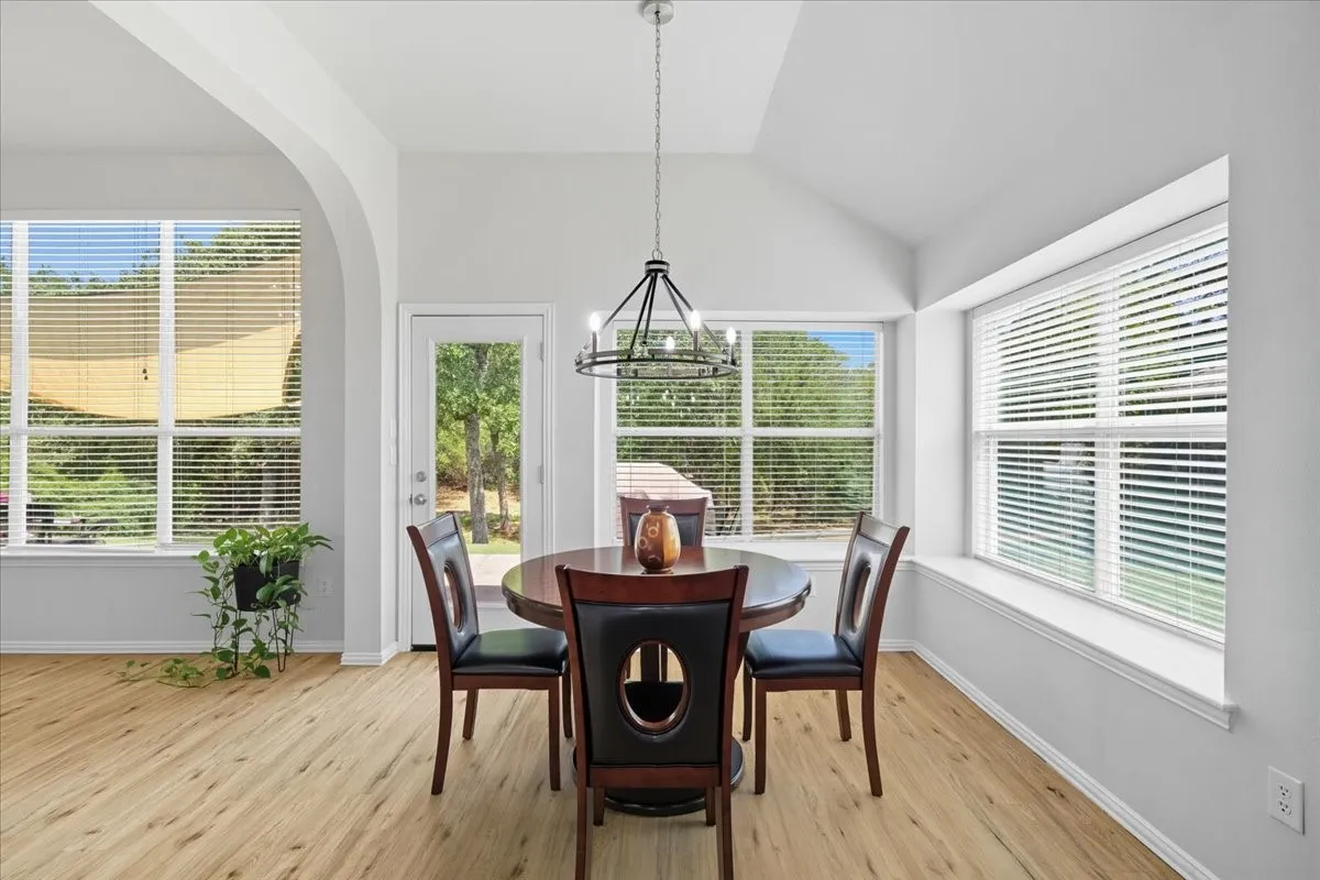 Vaulted ceilings, wood-finish flooring, arched doorway, and ample natural light from multiple windows