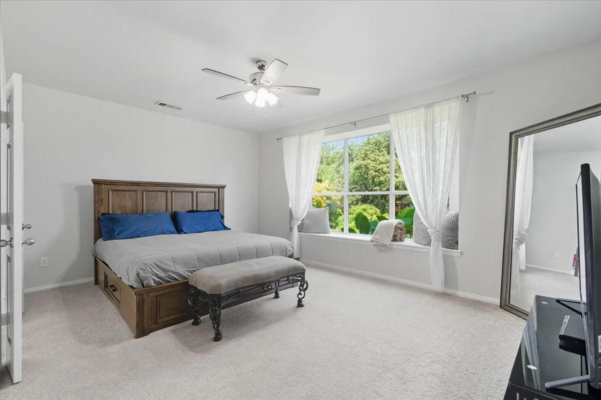 Expansive window with a window seat, ceiling fan, neutral carpet, and light-toned walls