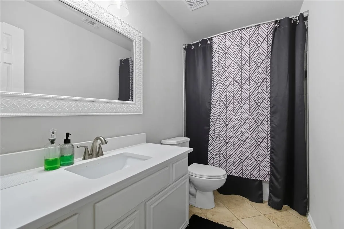 Single vanity with a white countertop and integrated sink, brushed nickel faucet, and decorative framed mirror