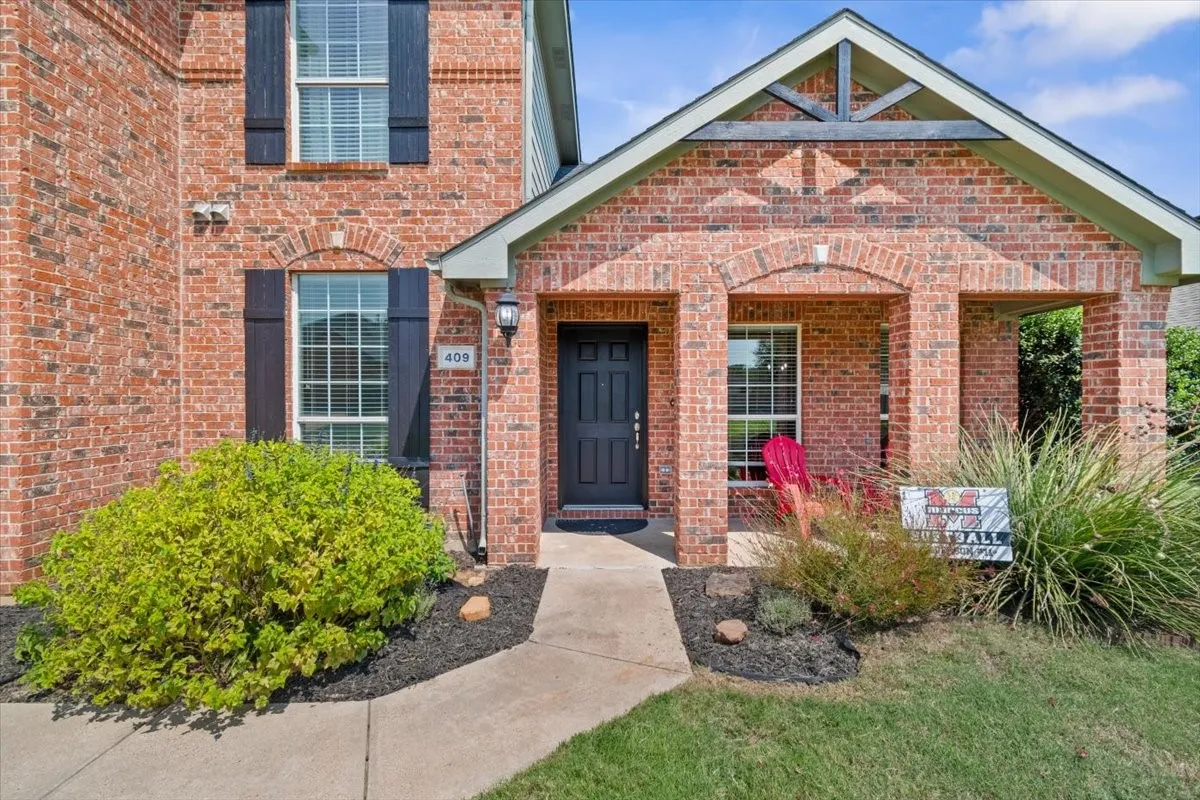 Brick exterior with an arched entryway, covered porch, and decorative shutters