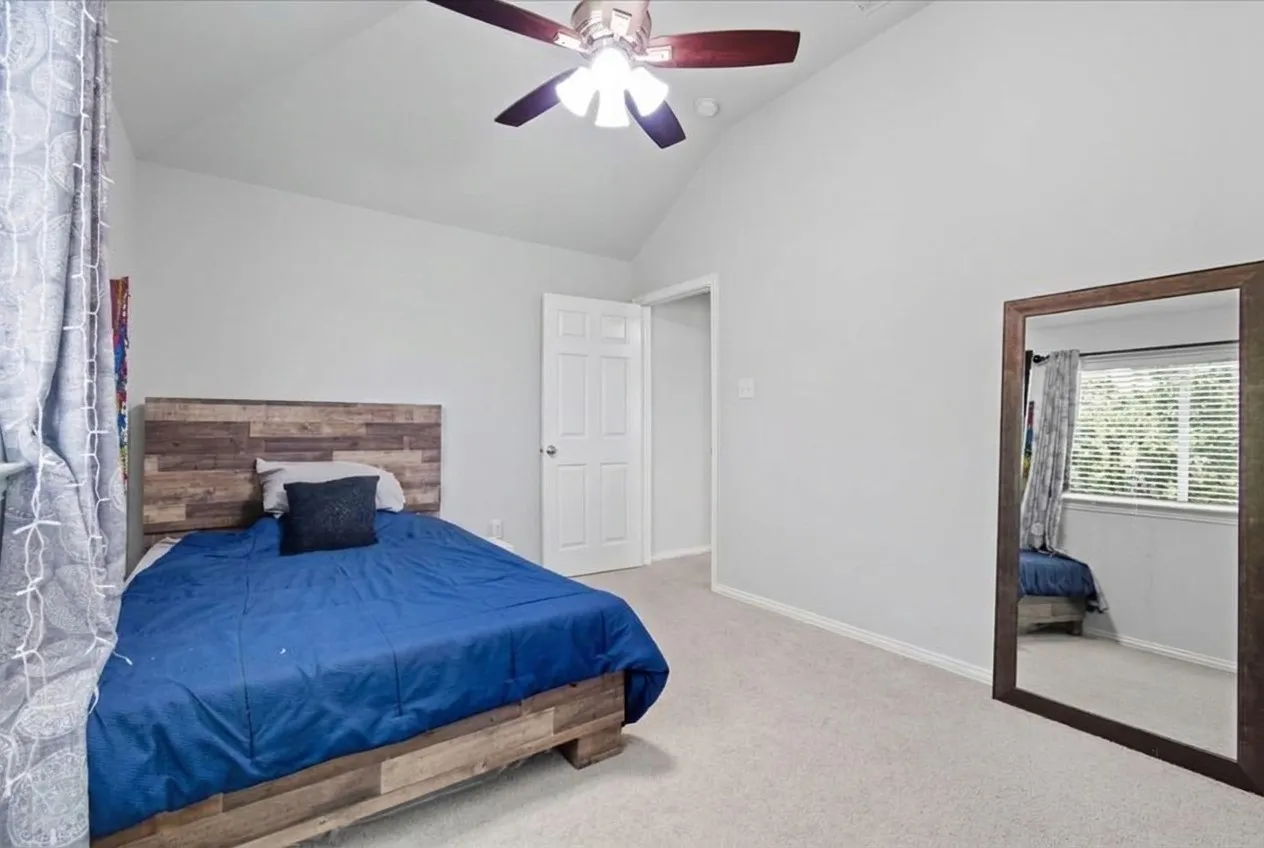 Vaulted ceiling with a ceiling fan, carpeted flooring, and a window with blinds