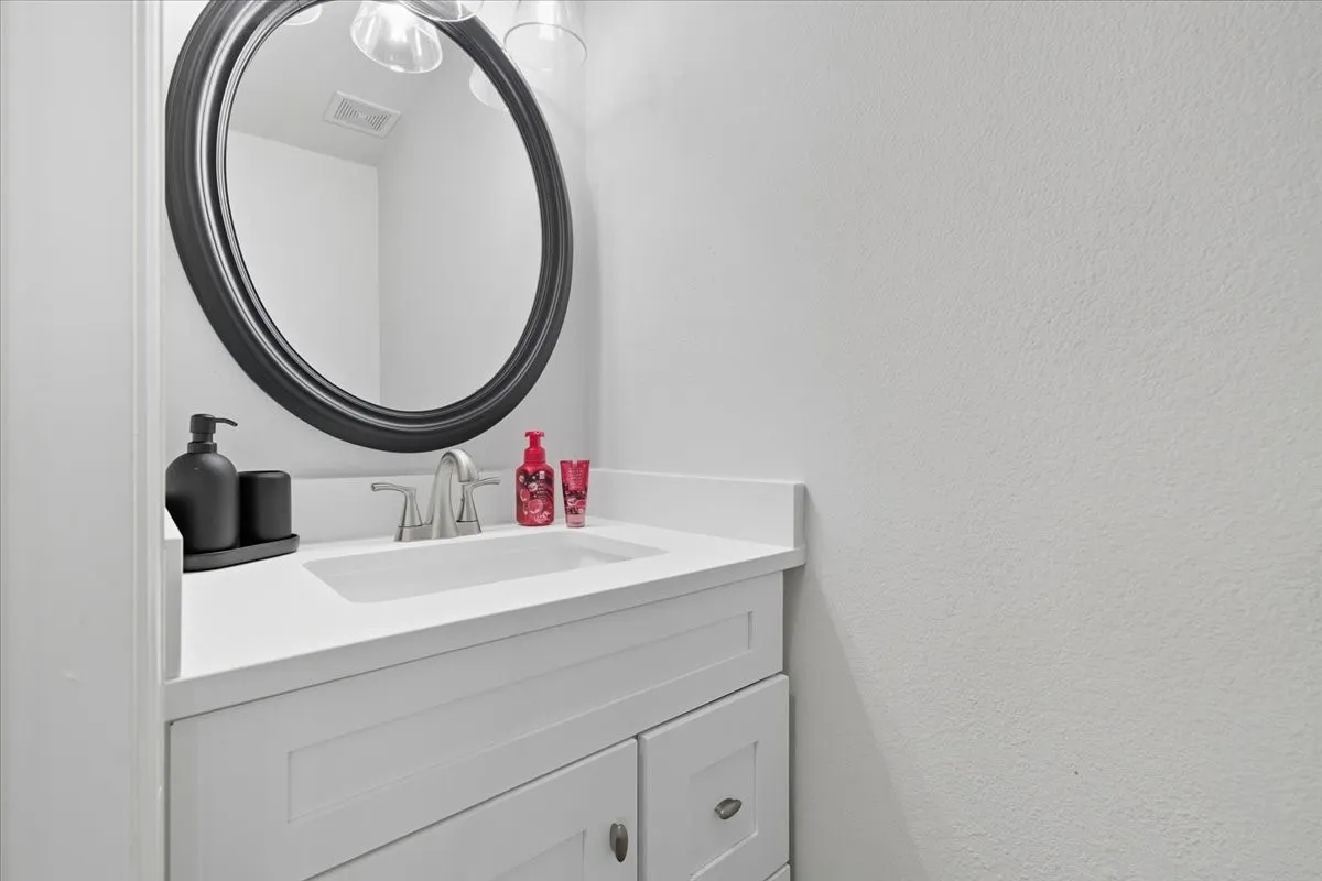 White vanity with shaker-style door and drawer fronts, single undermount sink, and brushed nickel faucet