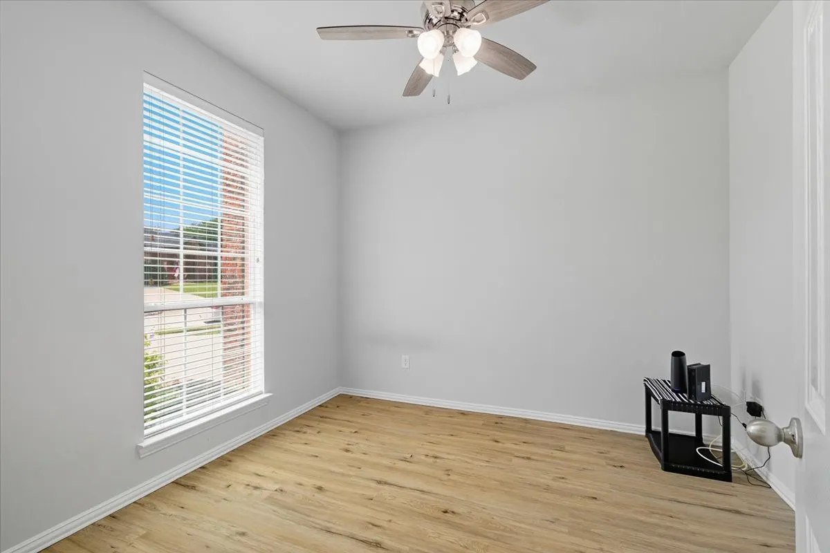 Generous window with white blinds, wood-finish flooring, ceiling fan with integrated lighting, and neutral wall tones