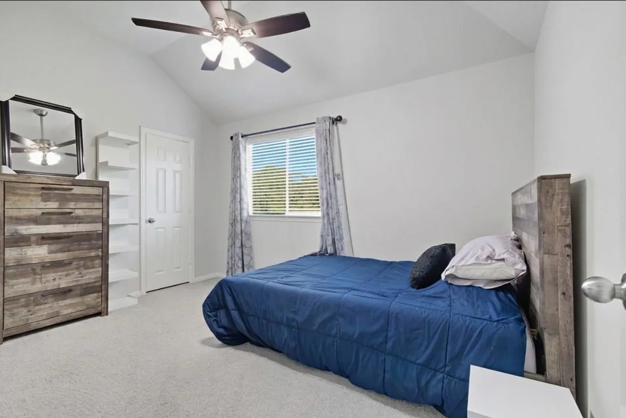 Vaulted ceiling, ceiling fan with integrated lighting, white paneled door, built-in shelving, and carpet flooring