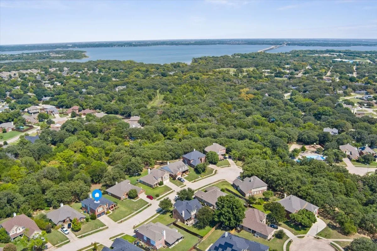 Expansive residential area featuring a prominent body of water, extensive tree coverage, and a bridge structure in the distance