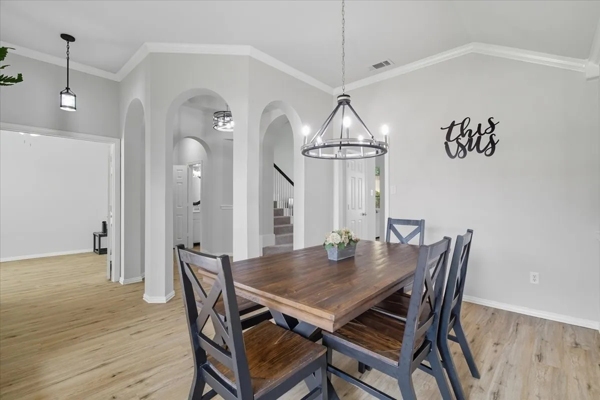Vaulted ceiling, crown molding, wood-finish flooring, recessed lighting, and arched doorways
