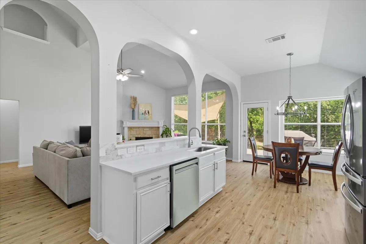 Kitchen with white cabinetry, light-colored countertops, stainless steel appliances, and wood-finish flooring