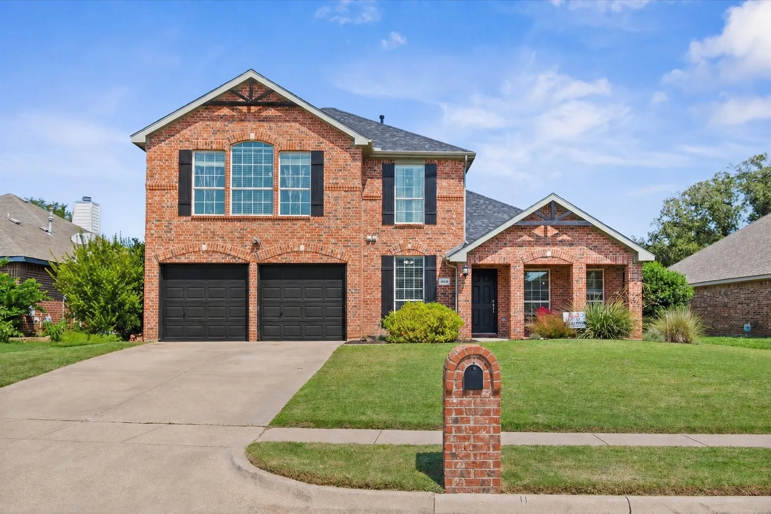 Brick facade, arched garage door openings, two-car garage, covered entry, and gabled roofline