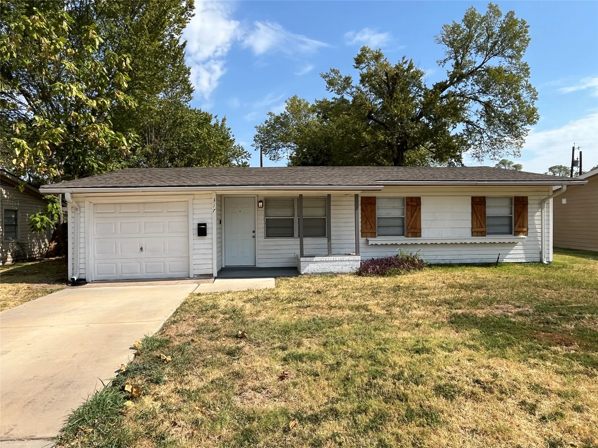 Charming single-story residence featuring a white exterior, attached two-car garage, and covered front porch entry
