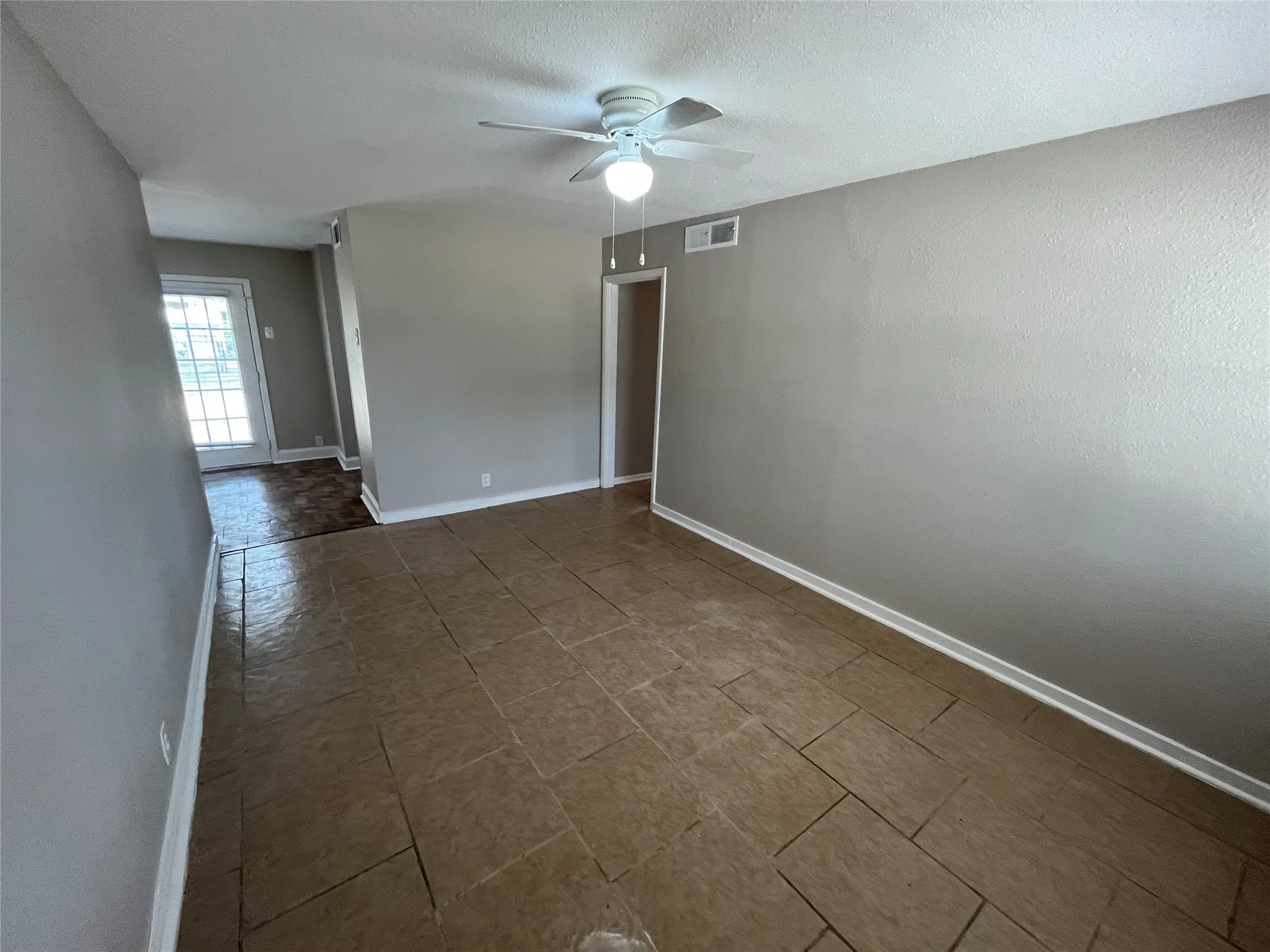Neutral wall paint, ceiling fan, and tile flooring