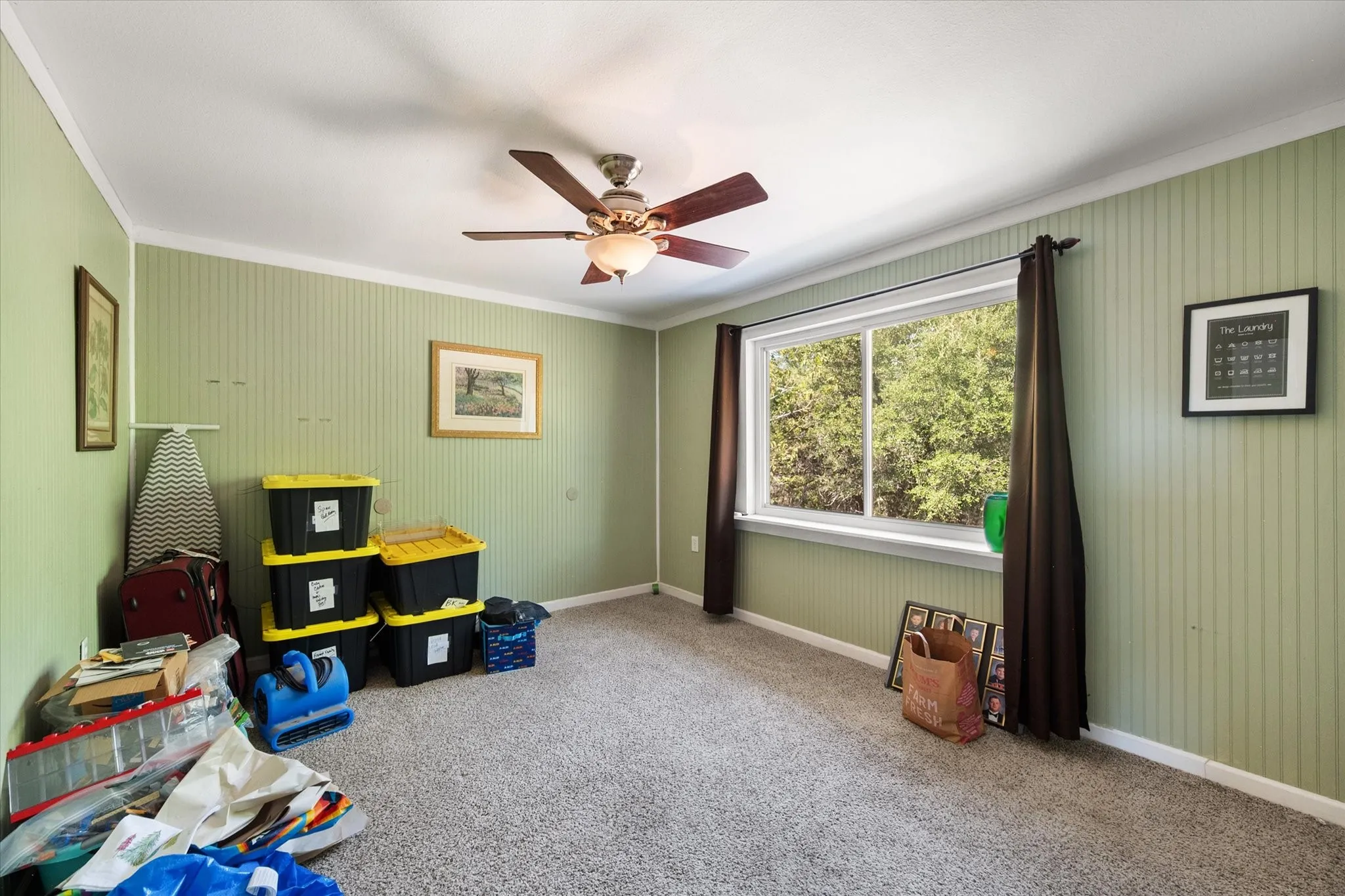 Textured wall covering, carpet flooring, a ceiling fan with integrated lighting, and a large window