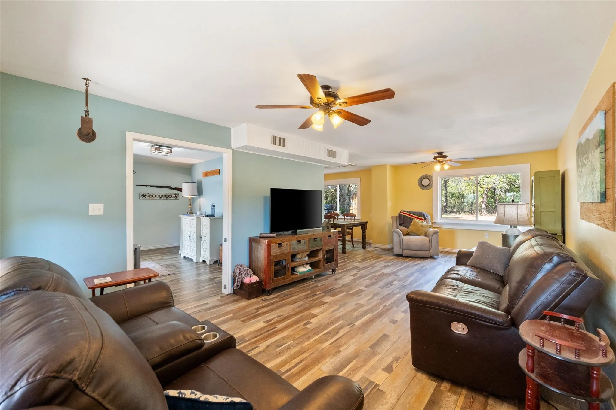 Wood-finish flooring throughout, multiple ceiling fans, and a window with outdoor scenery
