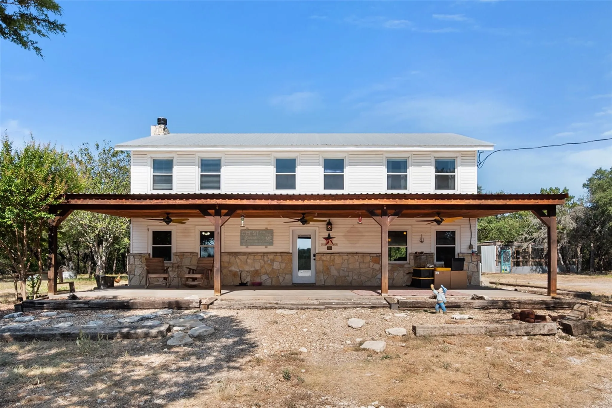 White siding exterior with a metal roof and a stone foundation